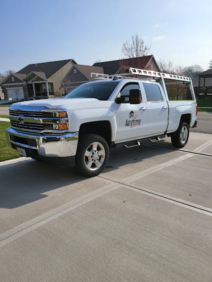 A white truck is parked on the side of the road in front of a house.