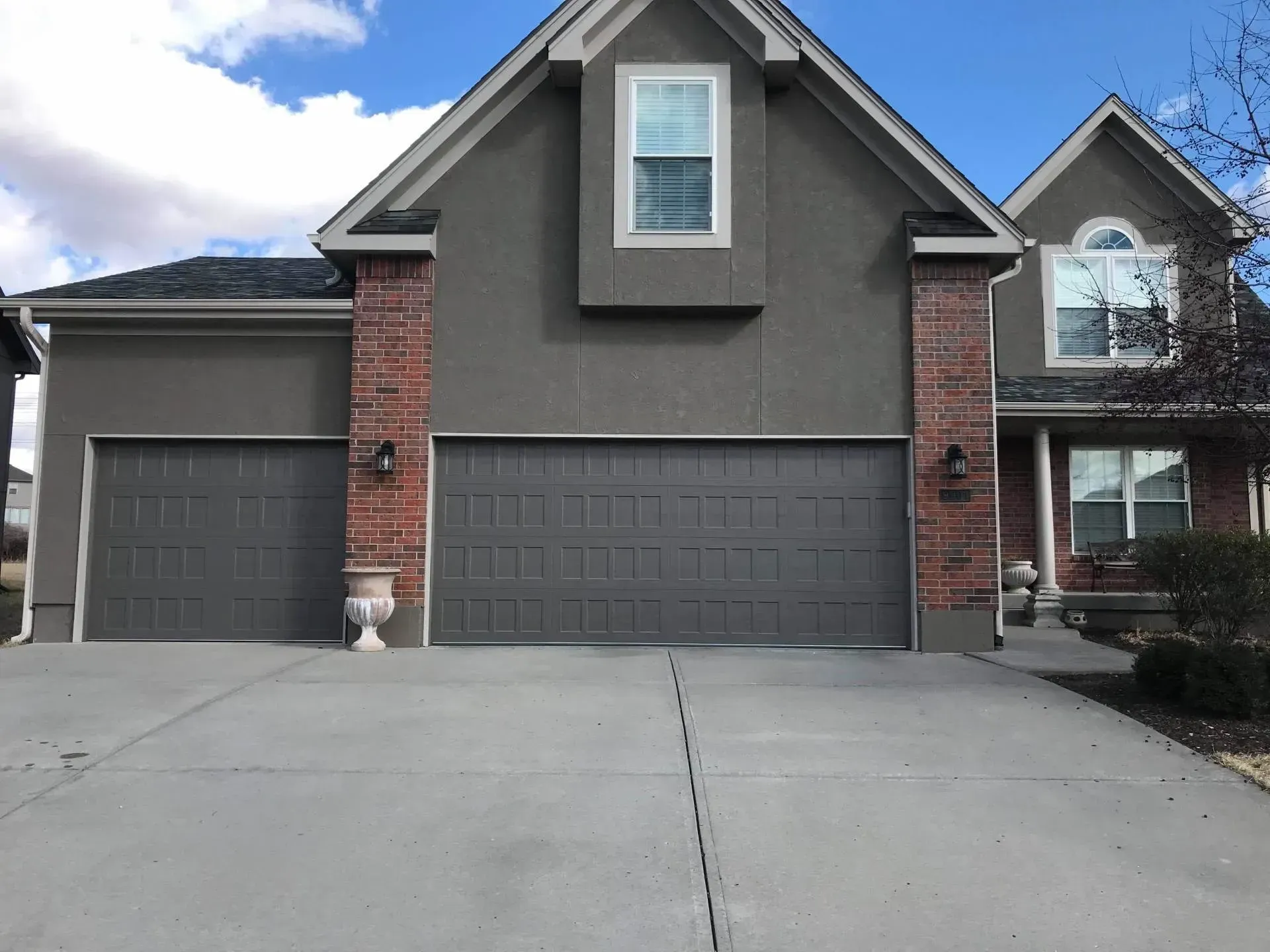 A large house with two garage doors and a brick wall