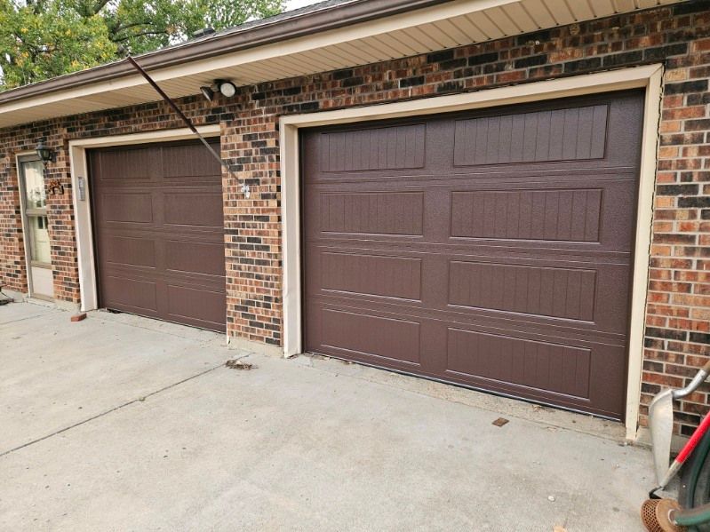 A couple of brown garage doors on a brick building.