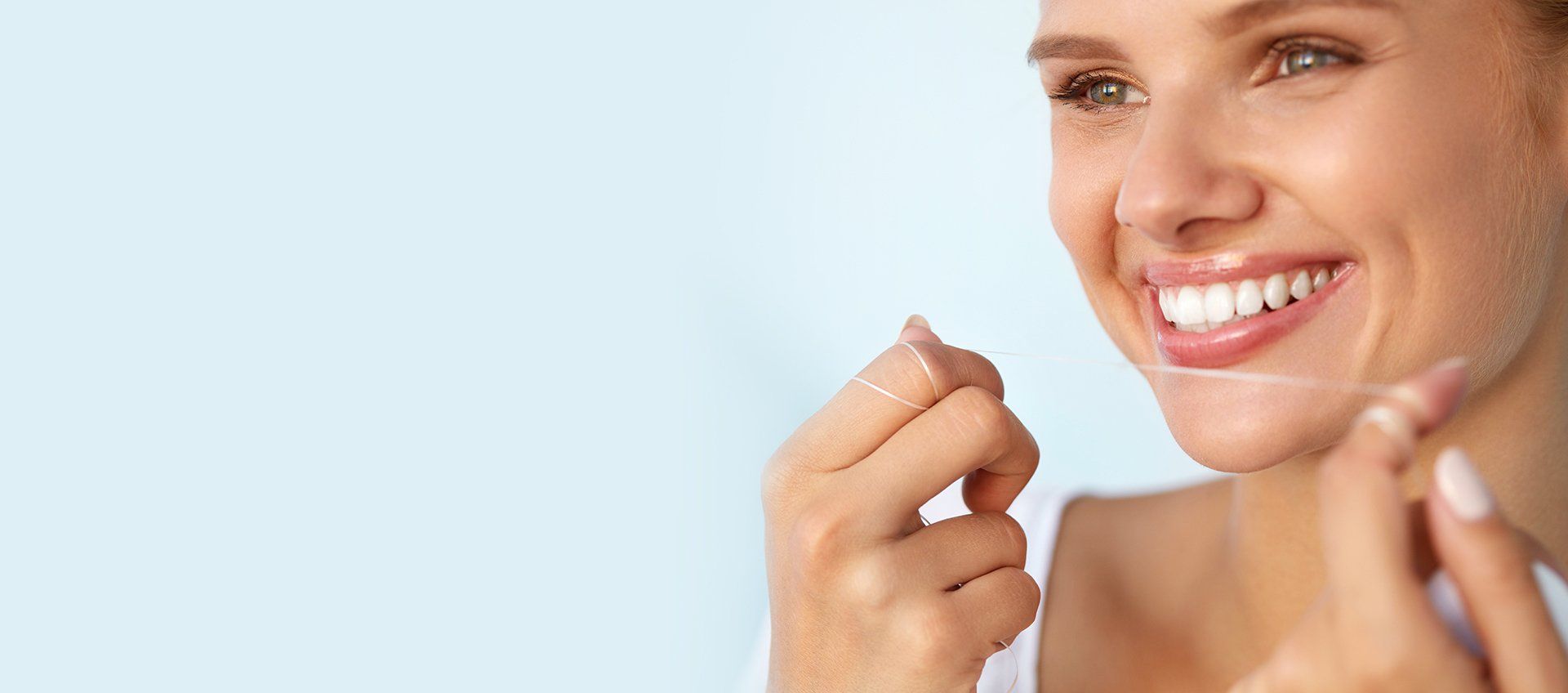 Woman smiling, holding teeth whitening strips.