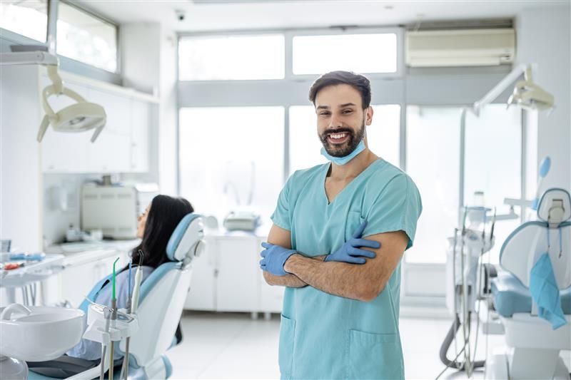 Dentist smiling warmly beside a patient in the dental chair Dentist smiling warmly beside a patient in the dental chair