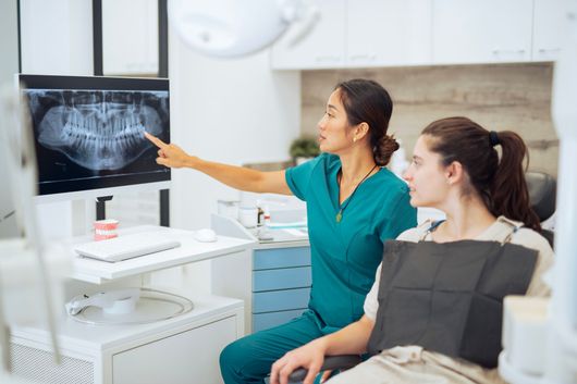 Dentist showing X-ray pictures to her patient during a dental appointment at a dental clinic.