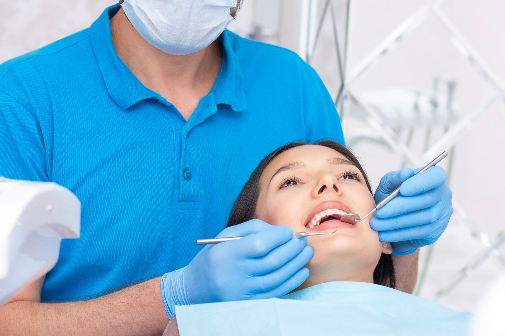 Dentist performing oral checkup with dental tools in a modern clinic setting.
