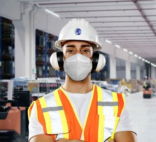 Obrero de la construcción subiendo una escalera, vistiendo un casco amarillo y un chaleco naranja, contra un cielo azul.