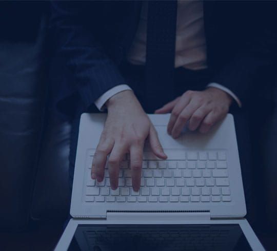 Obrero de la construcción subiendo una escalera, vistiendo un casco amarillo y un chaleco naranja, contra un cielo azul.