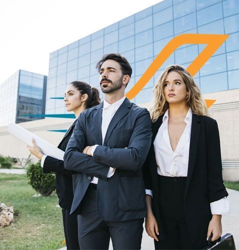 Tres profesionales de negocios de pie frente a un edificio moderno con un logotipo.