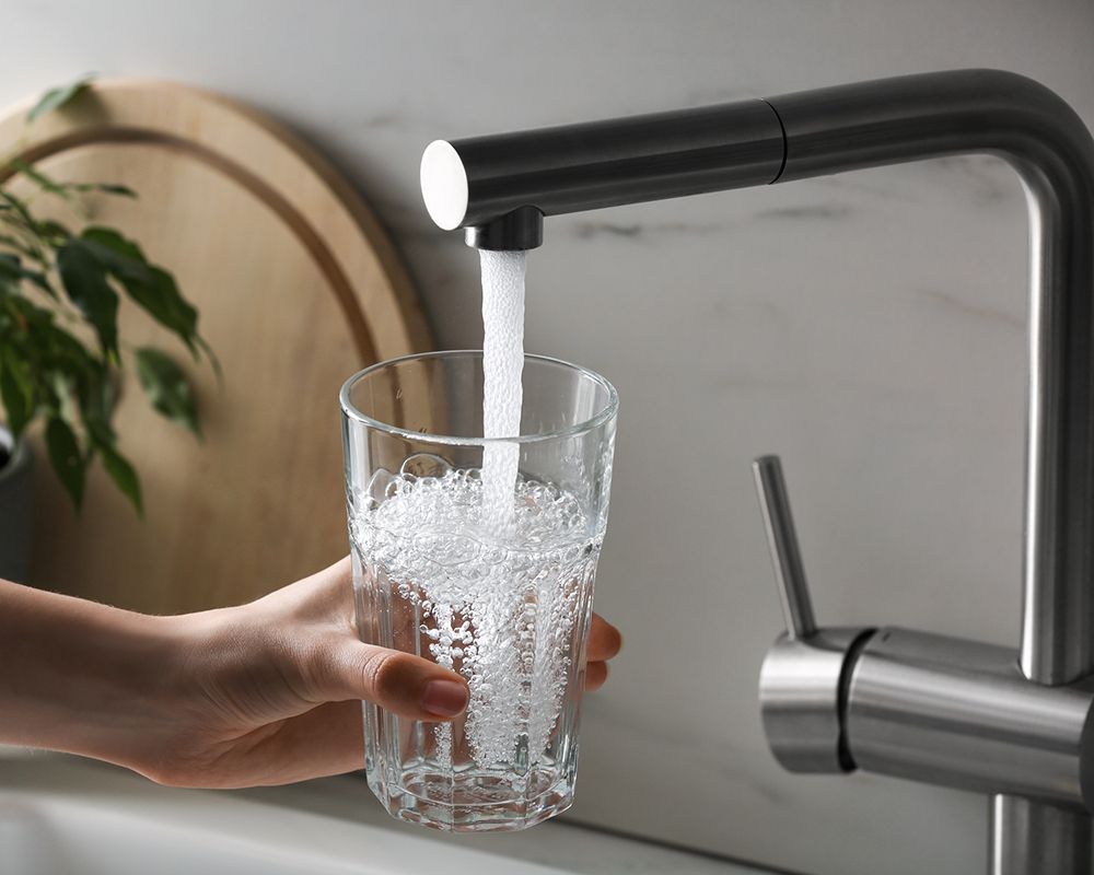 Woman is Pouring Water into a Glass from a Faucet – Cleburne, TX – Mr. Bill's Plumbing