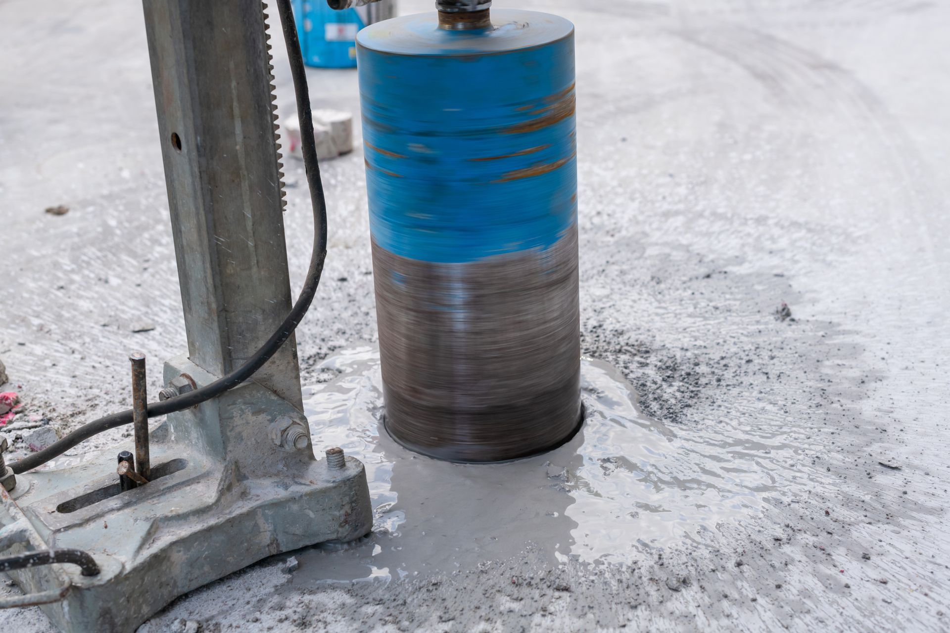 Core drill cutting a hole in concrete, spraying water.