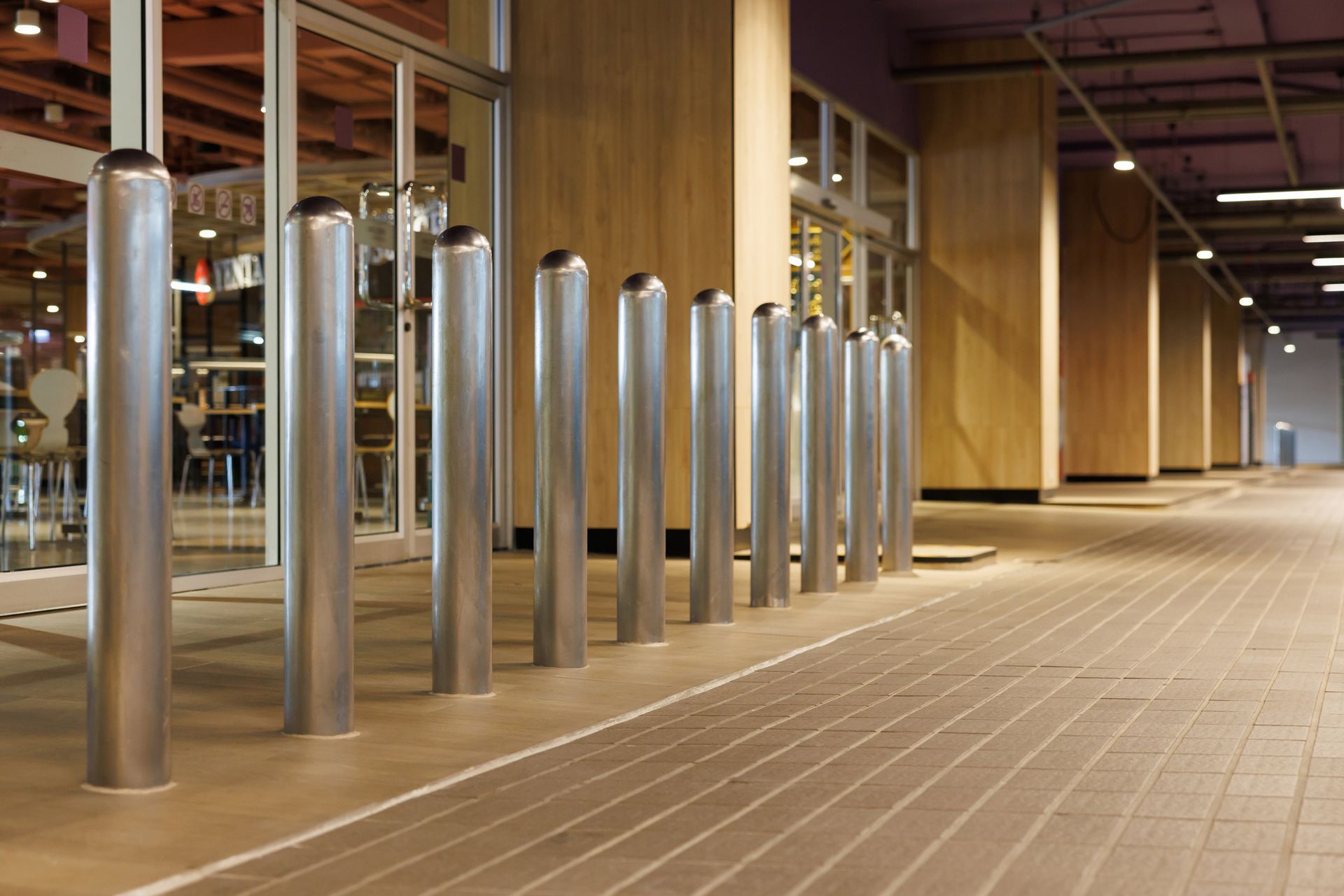 Row of metal bollards protecting the entrance of a building with glass doors, exterior view.