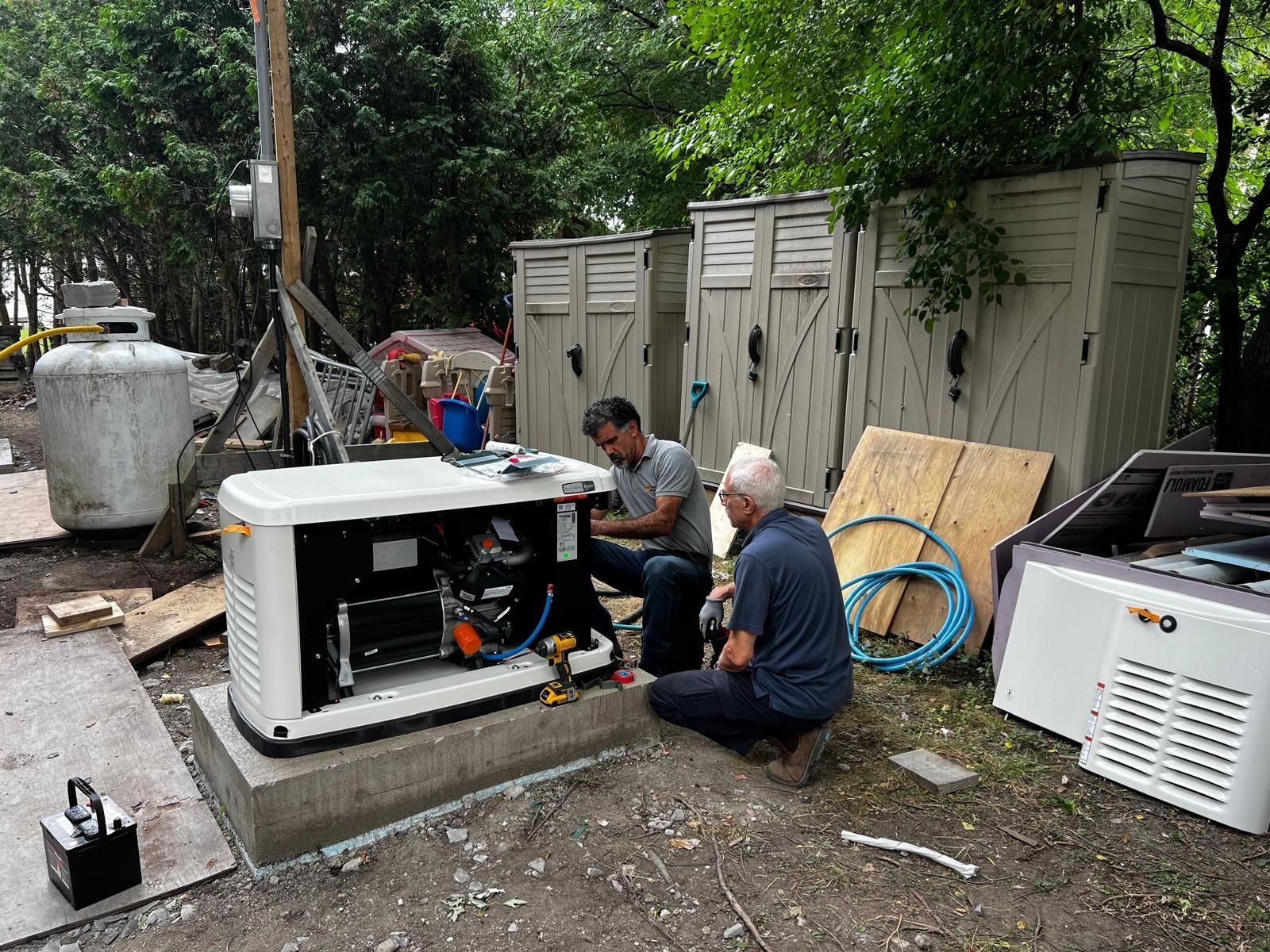 Two men working on a generator outside, near portable toilets and a propane tank.