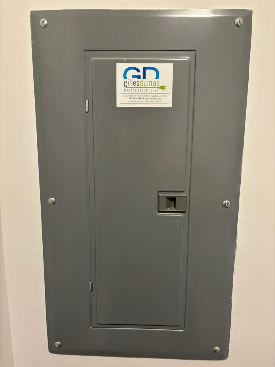 Gray electrical panel on a white wall with a company logo.