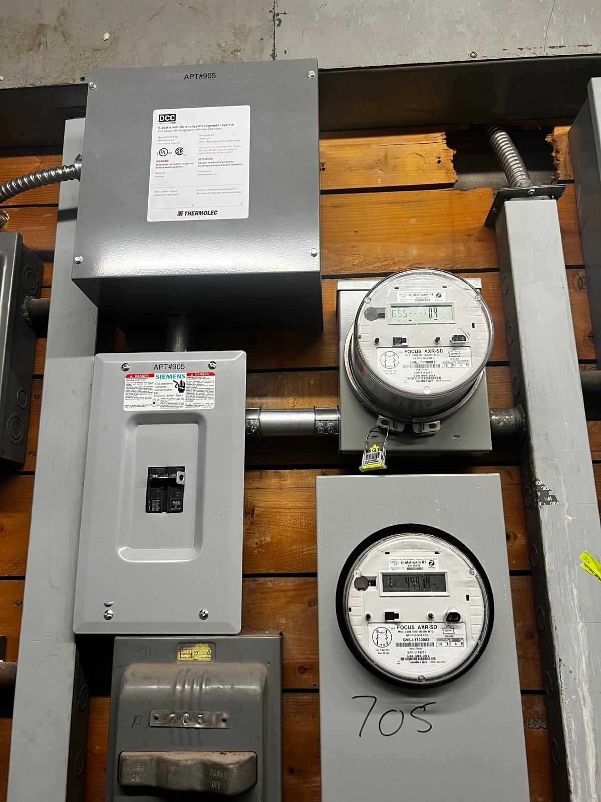 Electrical meters and panels mounted on a wooden wall.