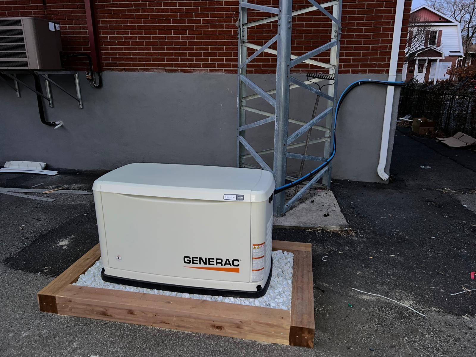 Générateur Generac sur cadre en bois à l'extérieur d'un bâtiment en briques, à côté d'une tour métallique.