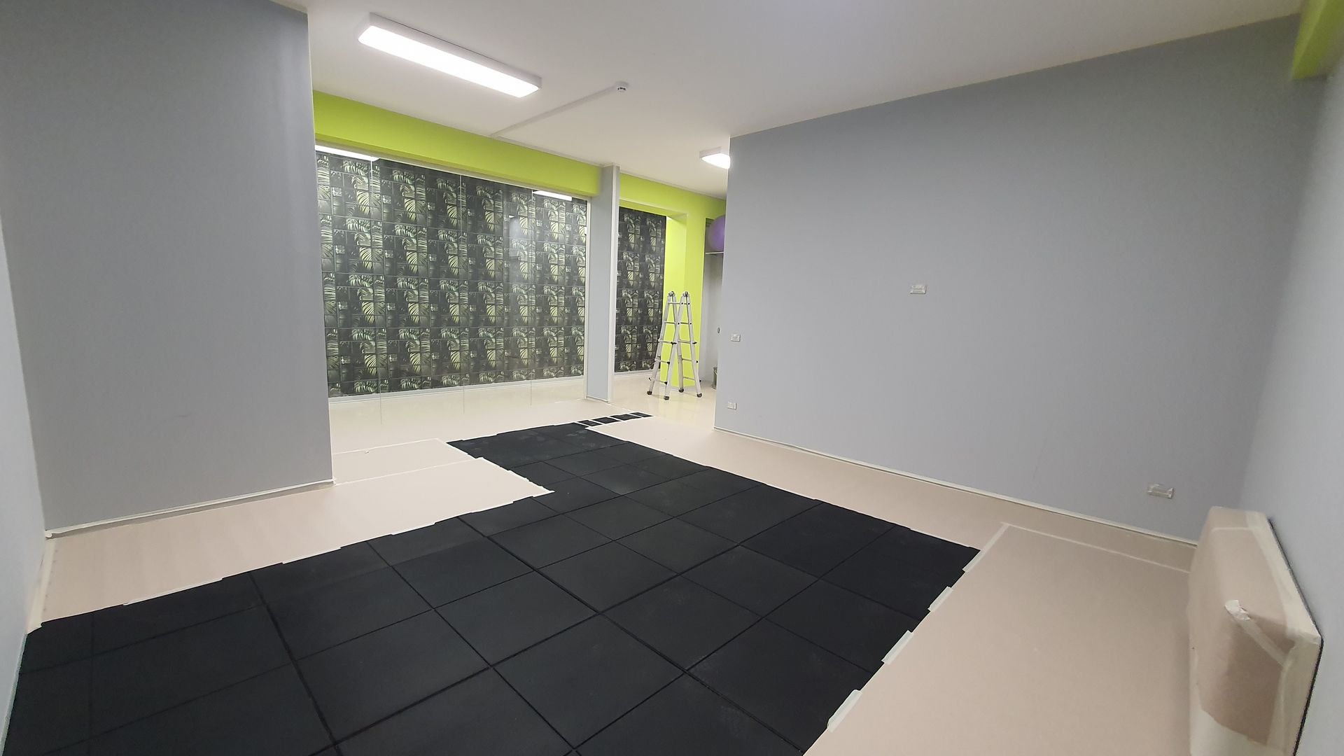 Una grande stanza vuota con uno zerbino nero sul pavimento.