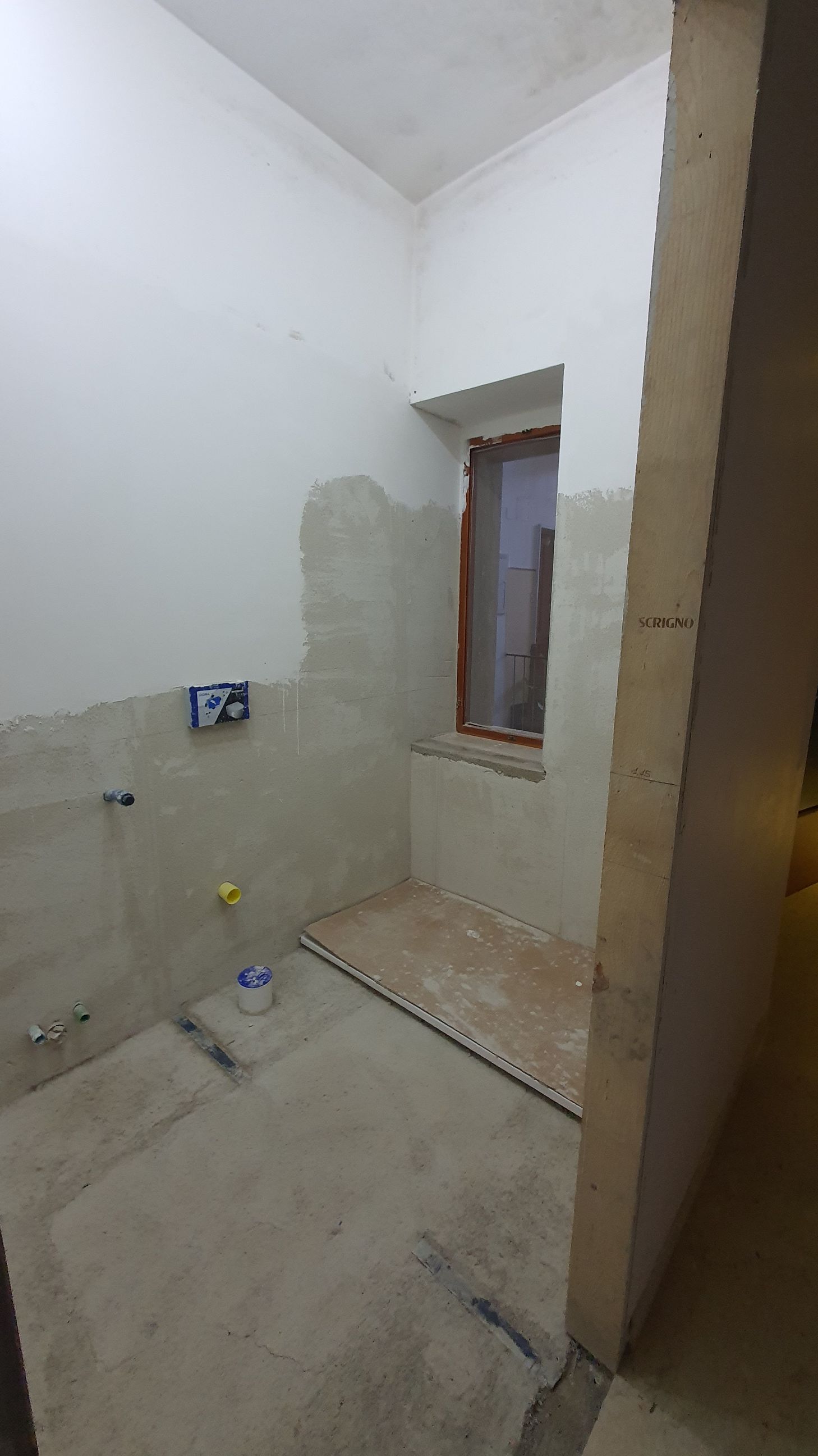 Un bagno in costruzione con una finestra e un pavimento in cemento.