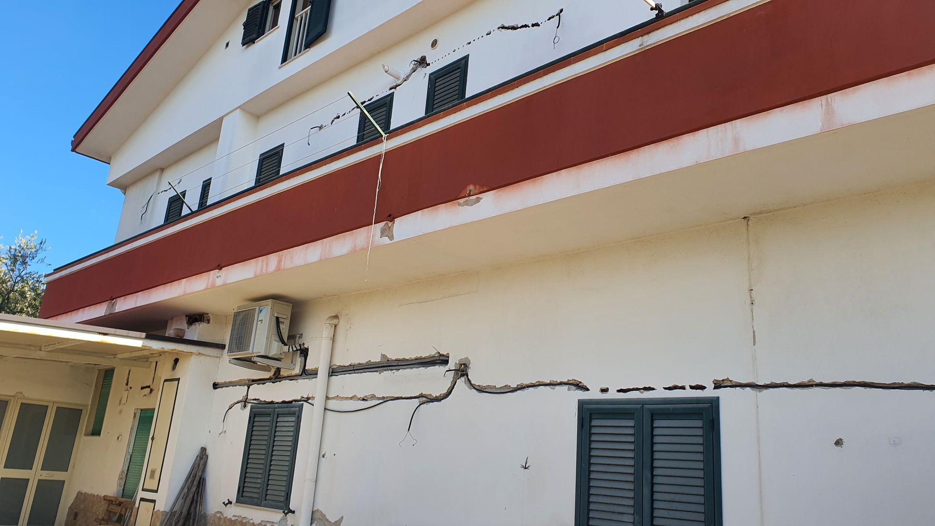 Un edificio bianco con il tetto rosso e le persiane alle finestre