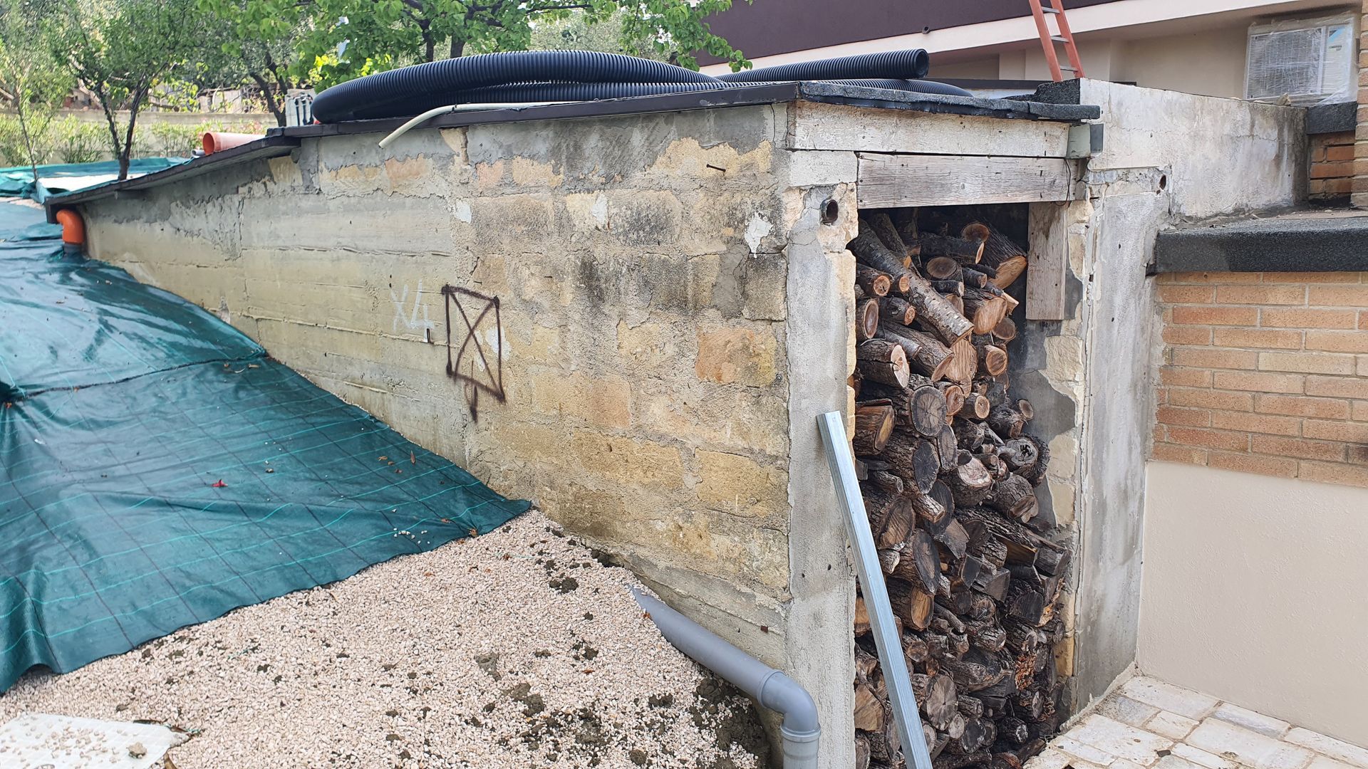 Una catasta di legna è posta accanto a un muro di mattoni.