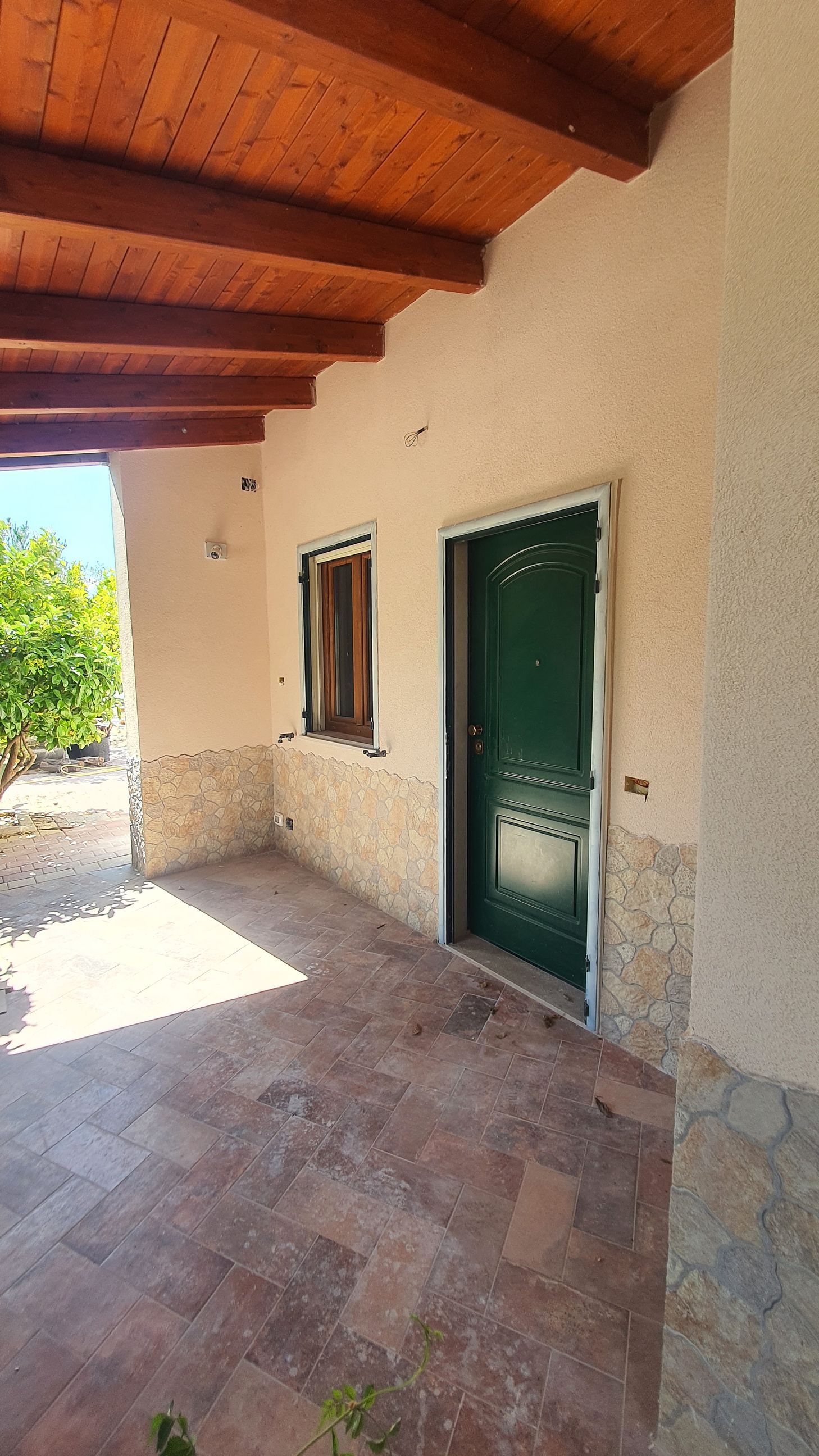 Una casa bianca con una porta verde e un soffitto di legno.