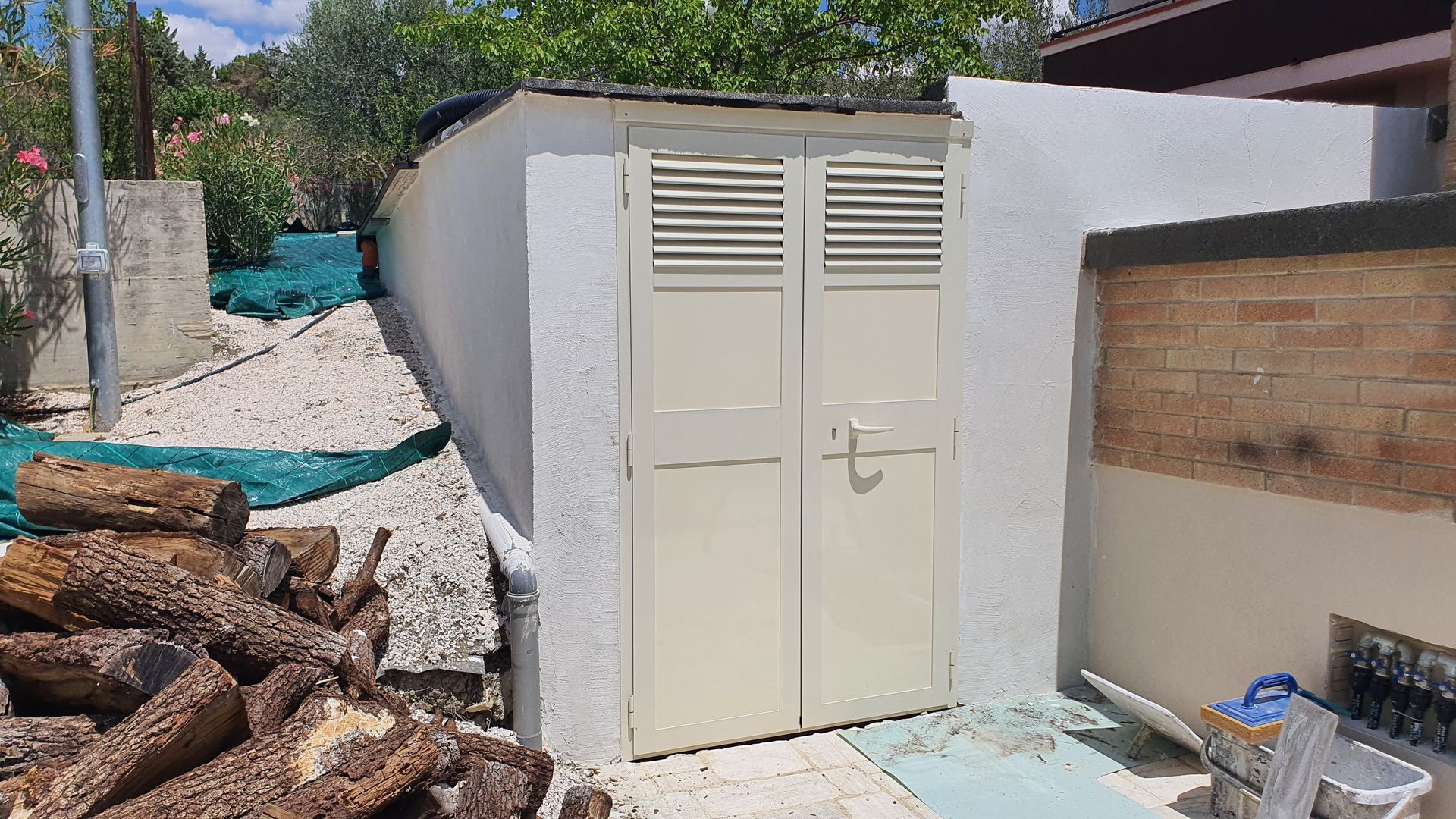 Una tettoia bianca è appoggiata accanto a una catasta di tronchi.