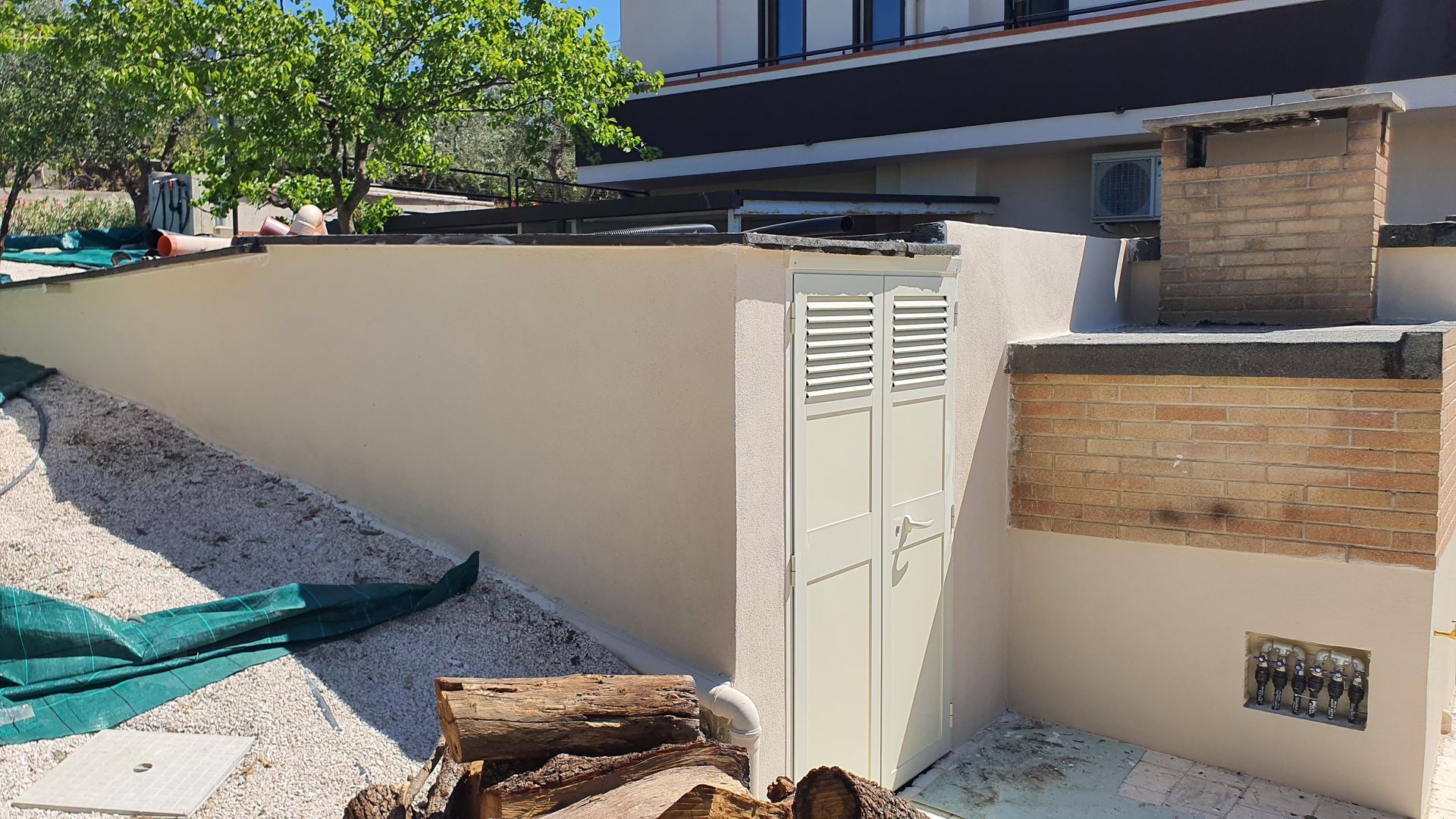 Una catasta di tronchi è posta di fronte a un muro bianco.