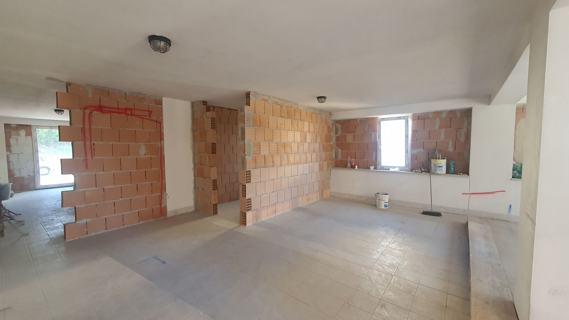Una grande stanza vuota con pareti di mattoni e pareti bianche.