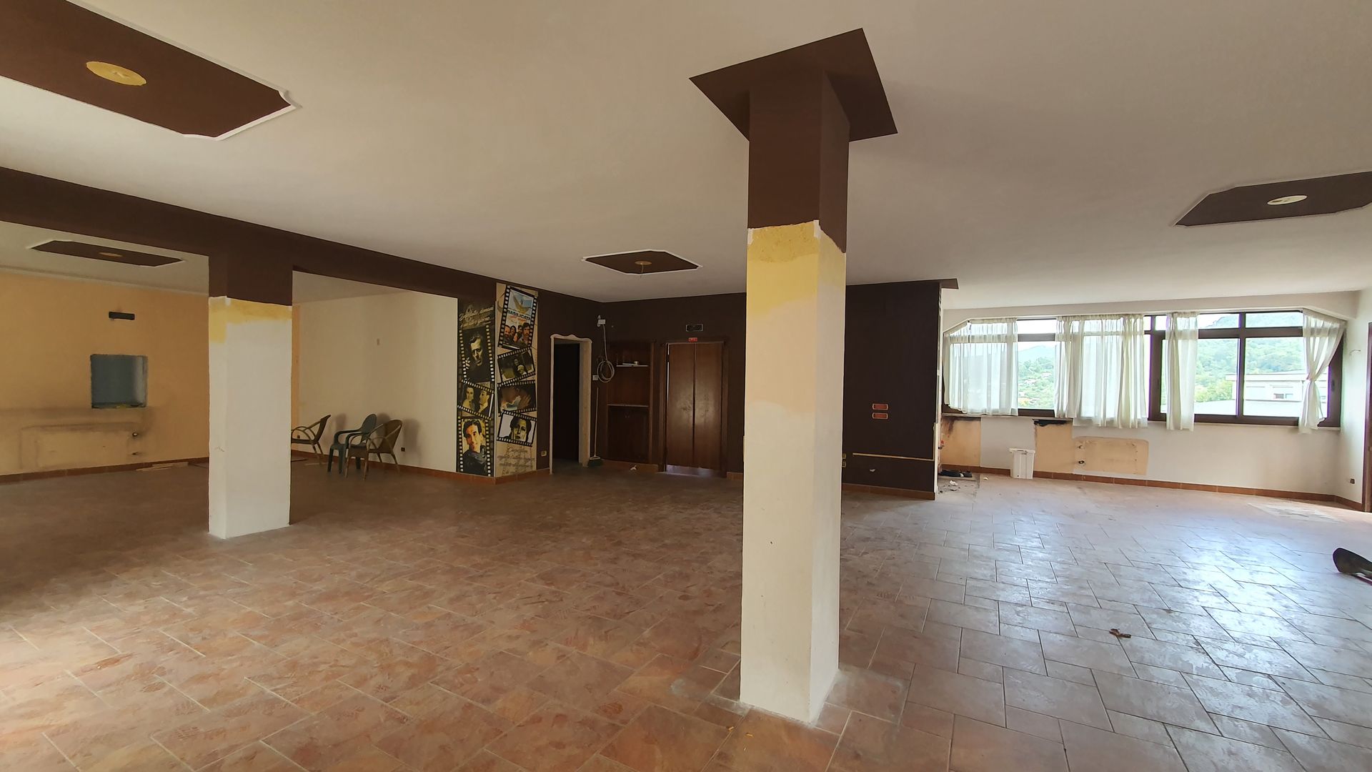 Una grande stanza vuota con colonne e pavimento piastrellato