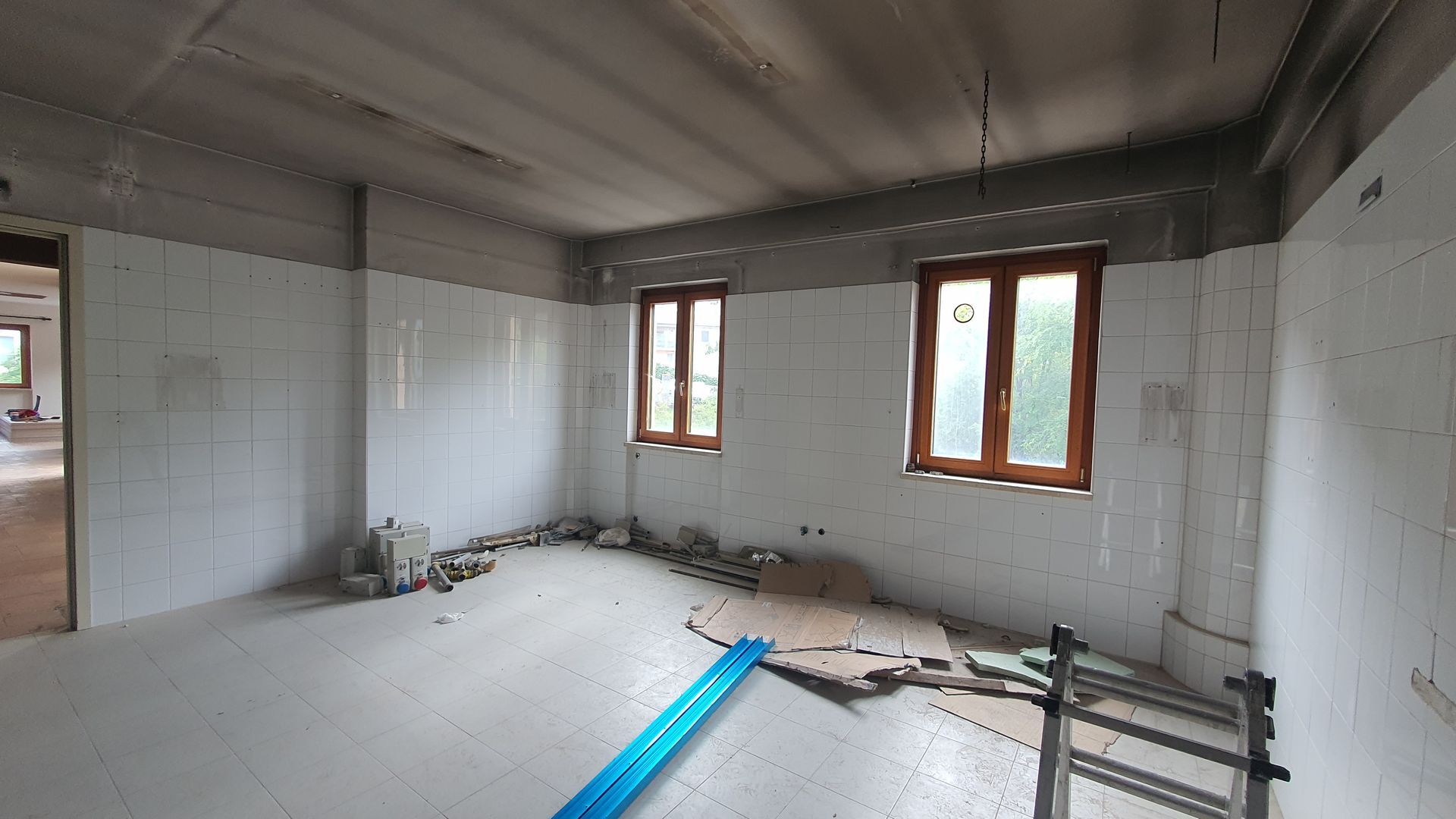 Una stanza vuota con piastrelle bianche e due finestre