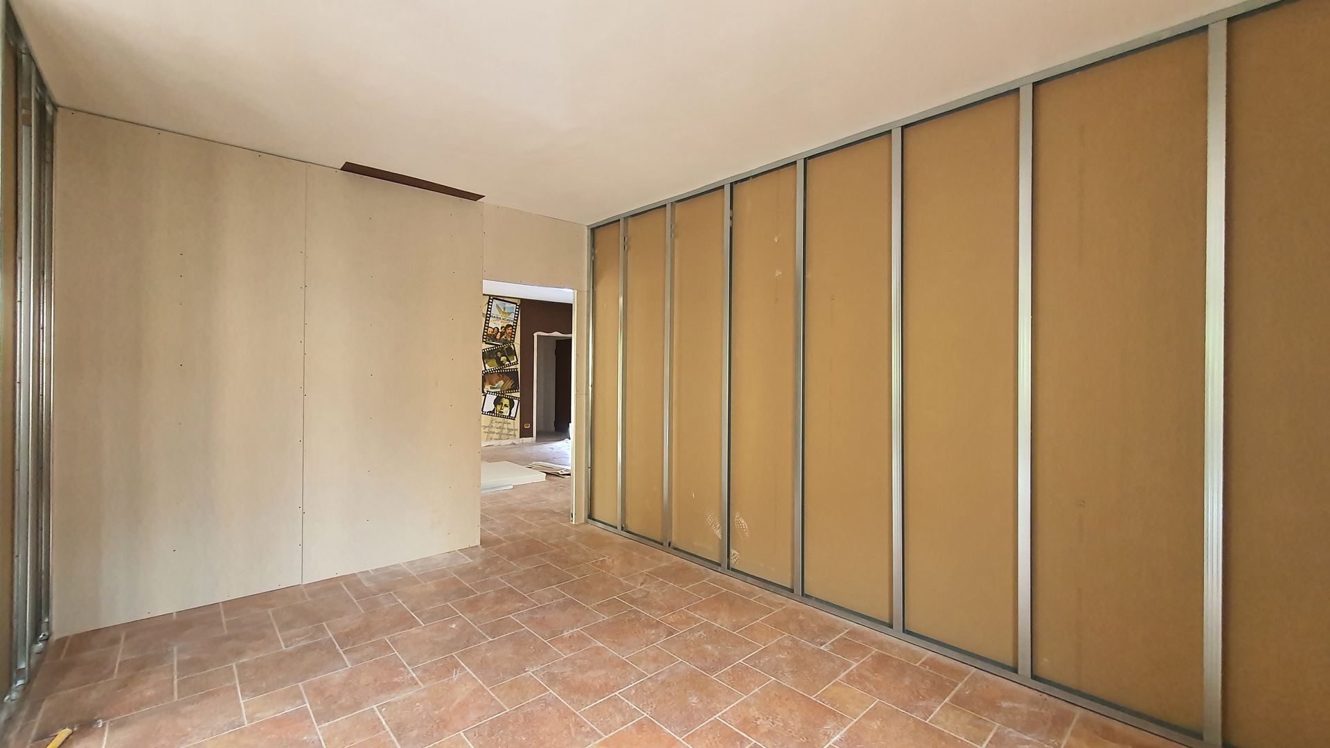 Una stanza vuota con pavimento piastrellato e pareti in costruzione.