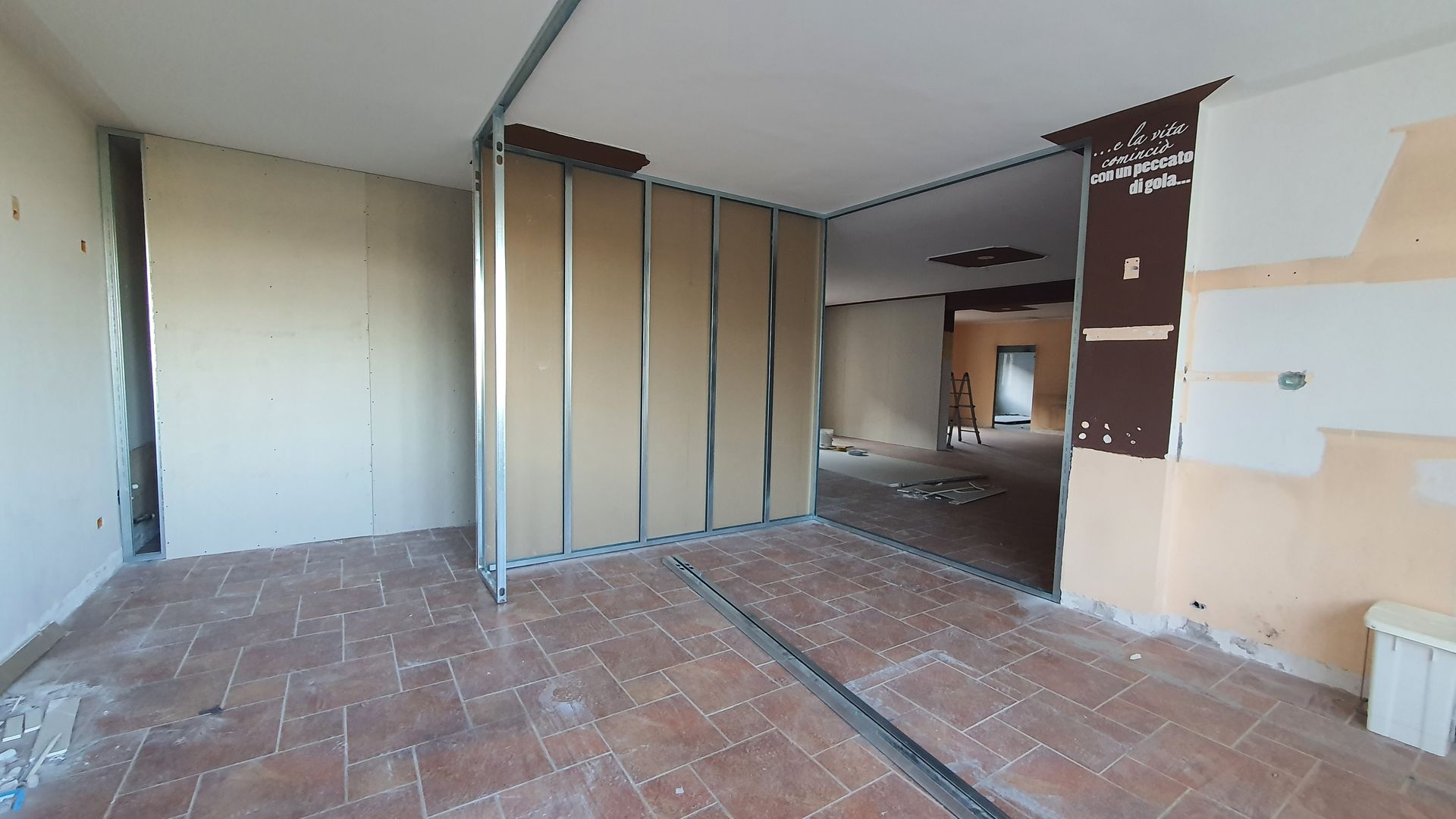 Una stanza vuota con un pavimento piastrellato e un muro di mattoni