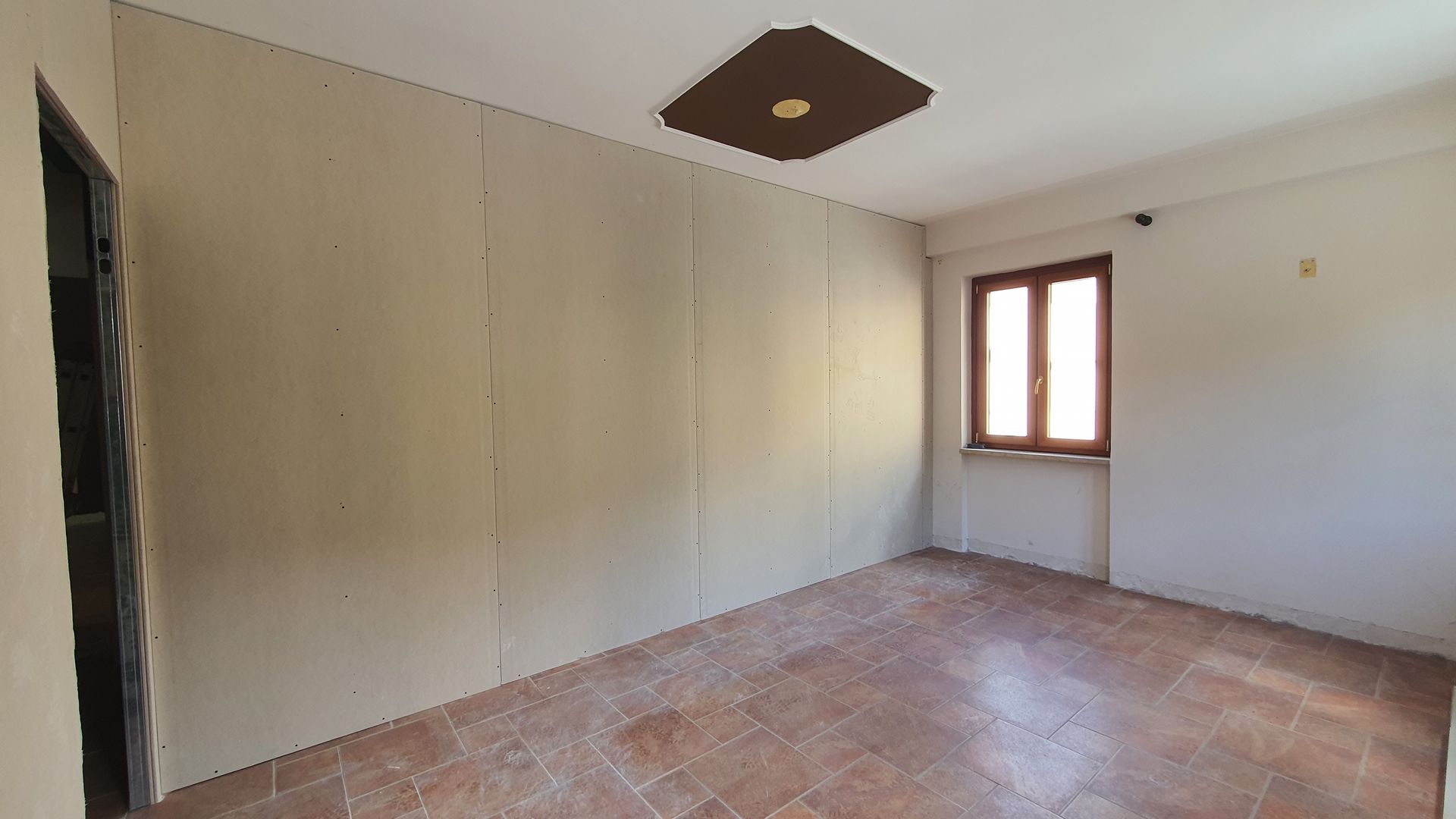 Una stanza vuota con pavimento piastrellato e una finestra.