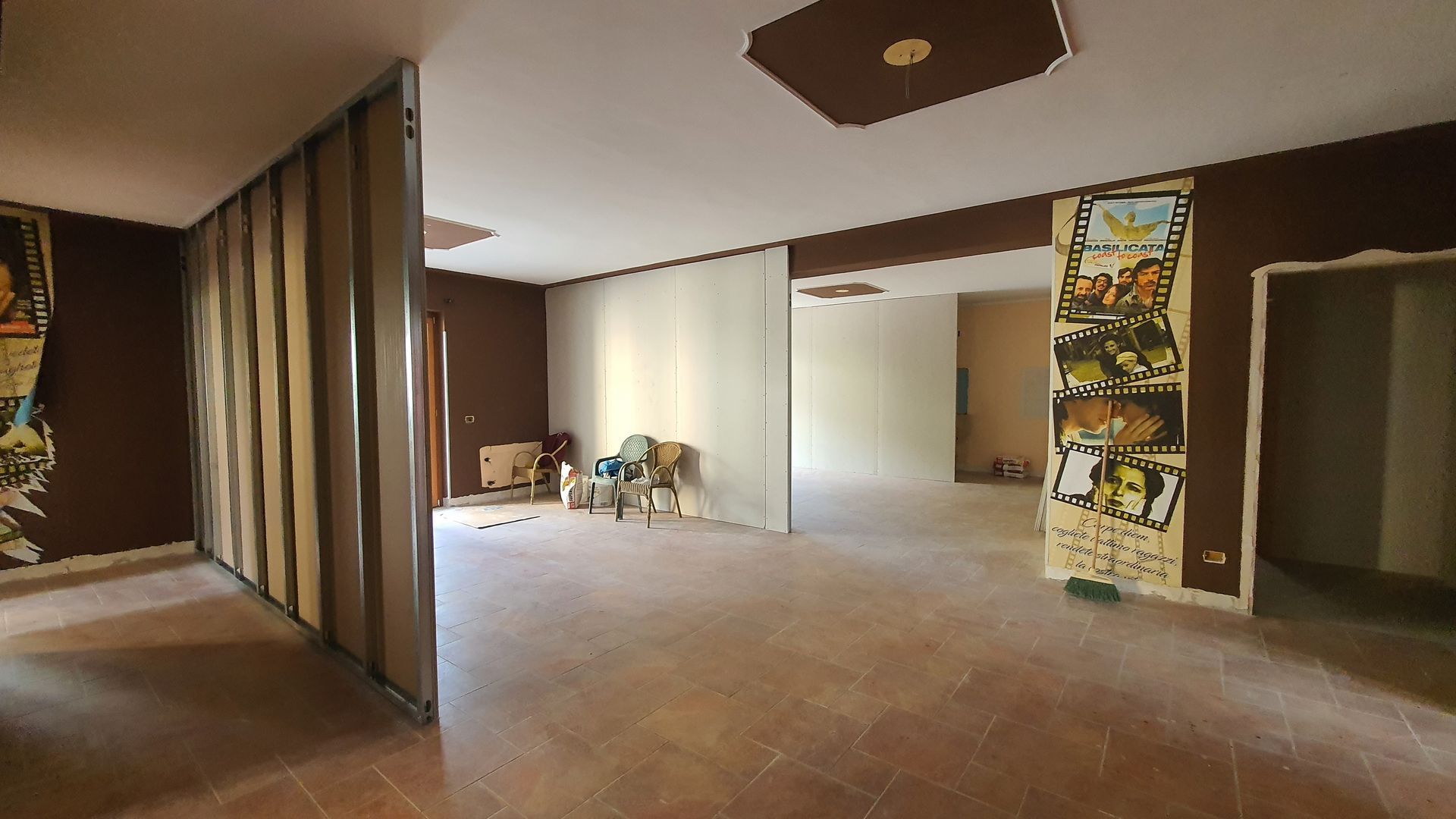 Una grande stanza vuota con un dipinto sul muro