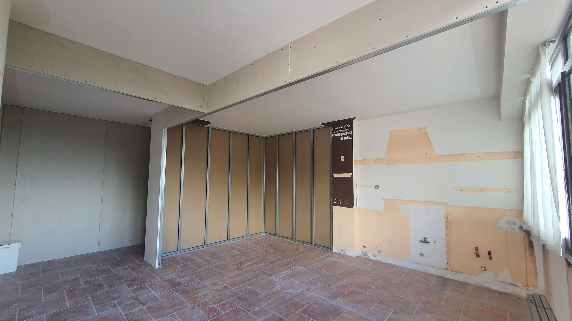 Una stanza vuota con pavimento in mattoni e pareti bianche.