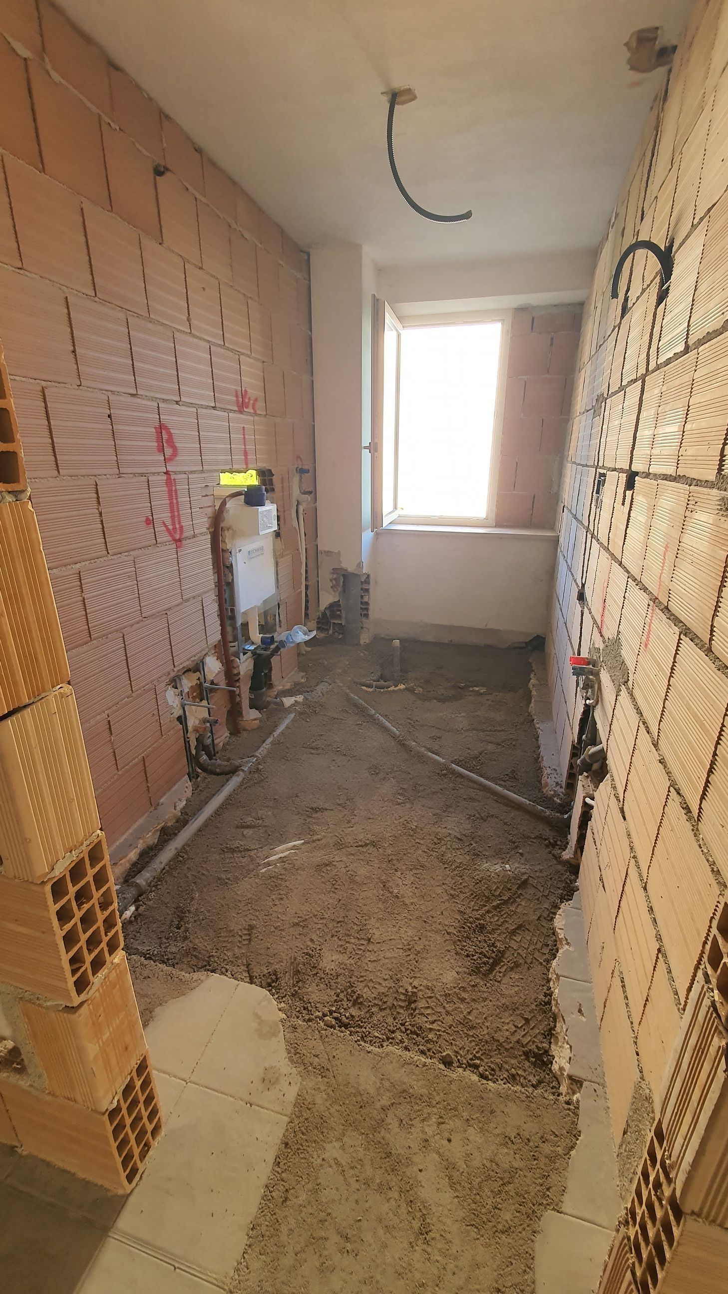 Un bagno in costruzione con pareti in mattoni e una finestra.