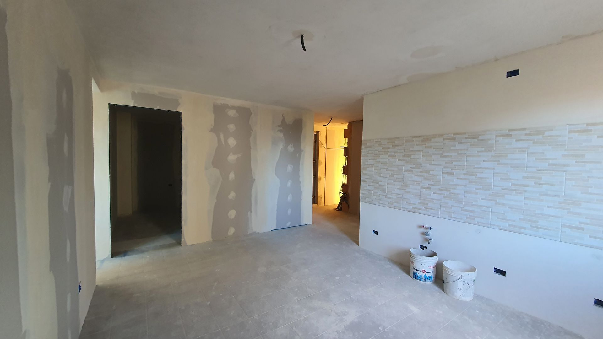 Una stanza vuota con un secchio di vernice sul pavimento