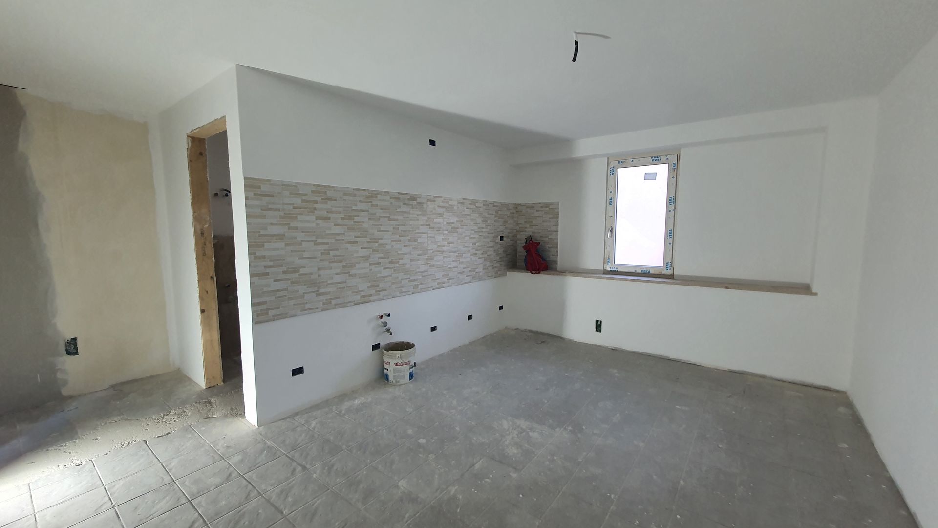 Una grande stanza vuota con pareti bianche e una finestra.