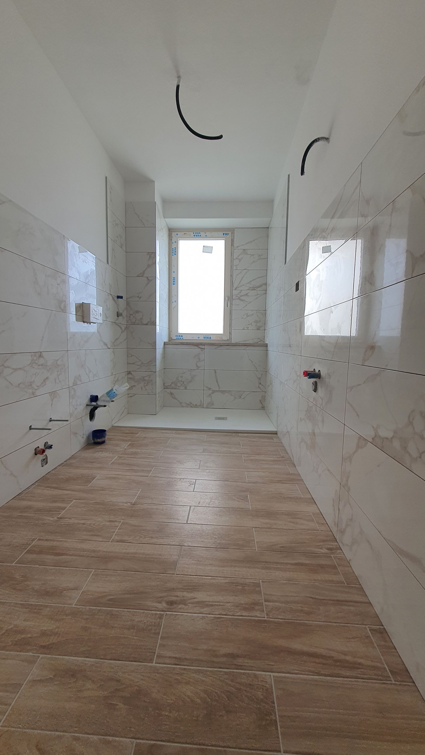 Una cucina vuota con pavimento in legno e piastrelle bianche.