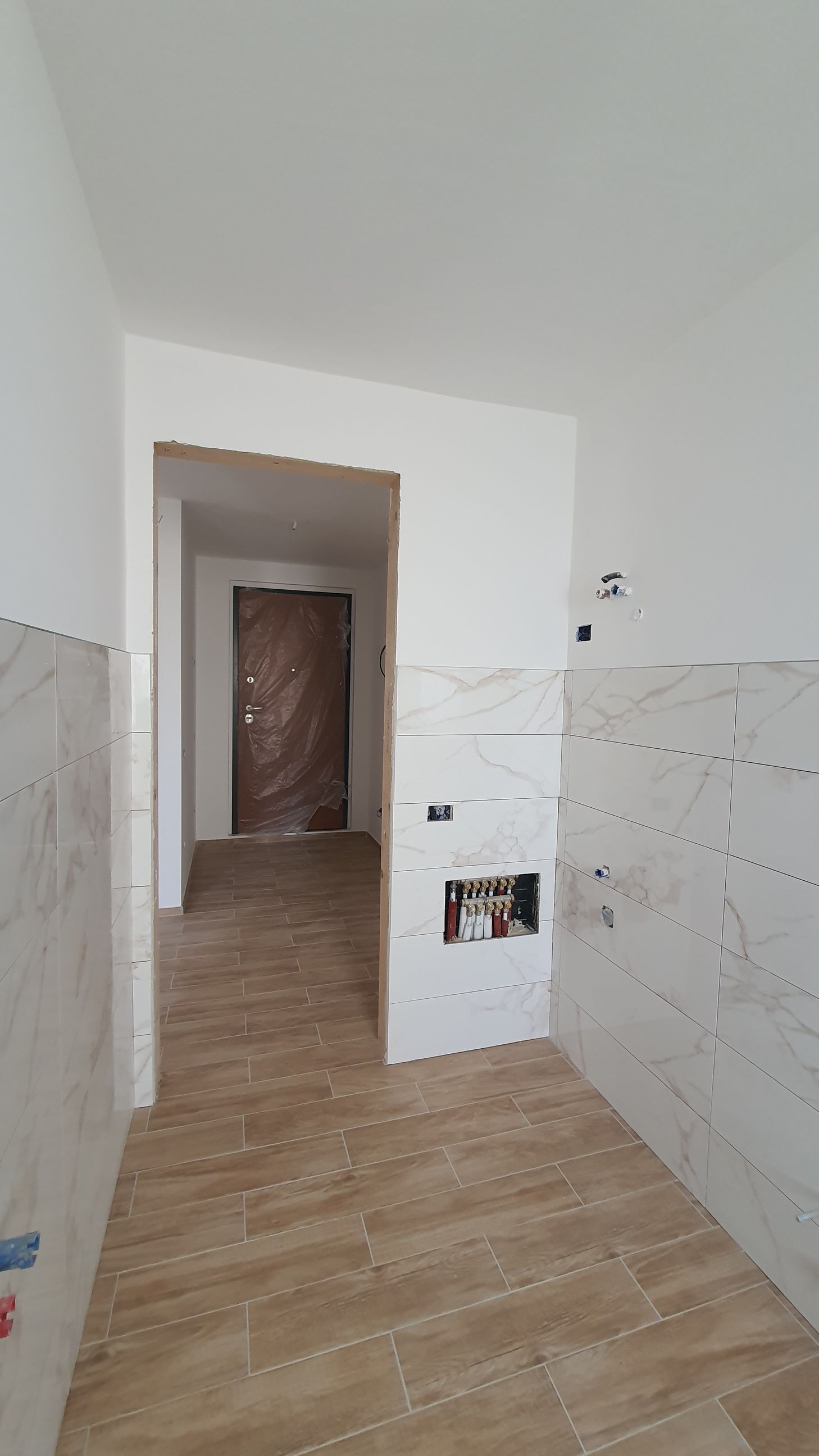 È in fase di ristrutturazione una cucina con pavimento in legno e pareti bianche.