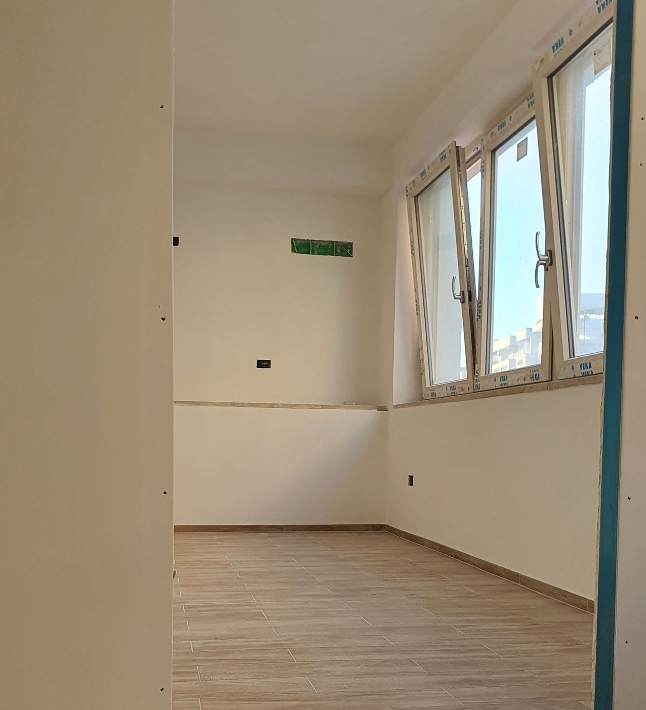 Una stanza con molte finestre e un pavimento in legno.