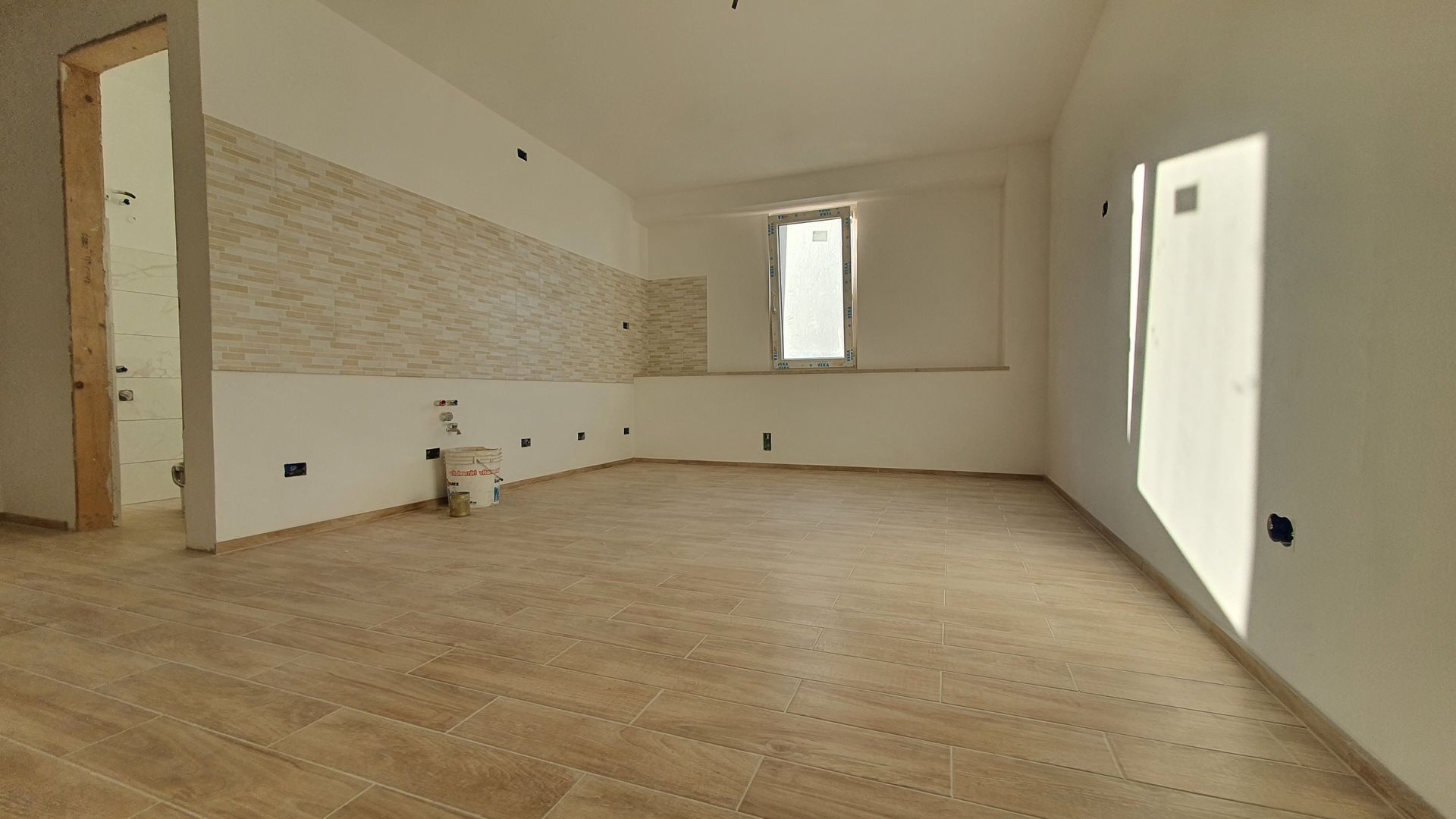 Una stanza vuota con pavimento in legno e pareti bianche.