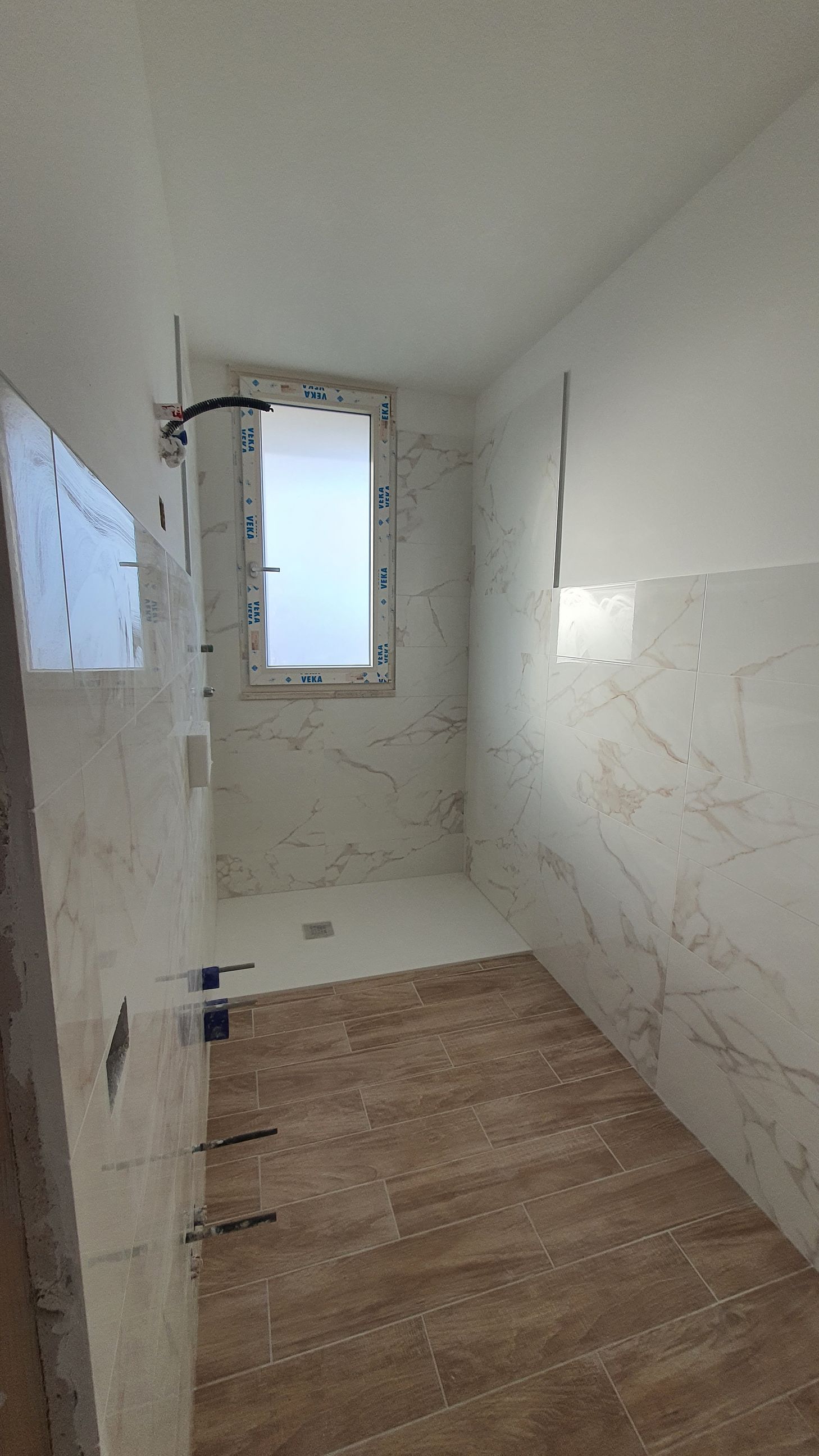 Un bagno con piastrelle di marmo e una finestra.