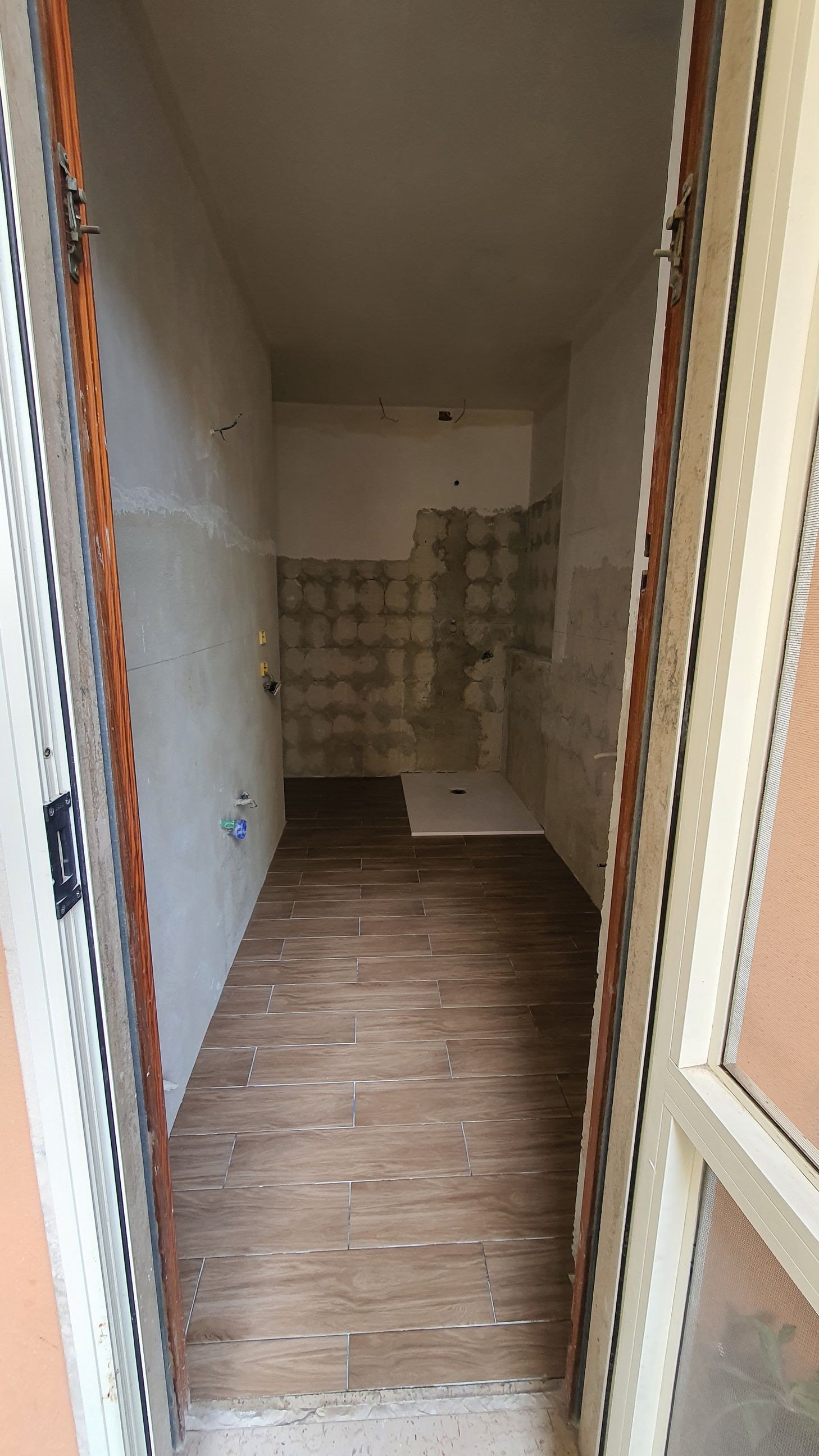 Una stanza vuota con un pavimento in legno e una porta.