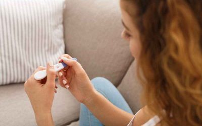 A woman is sitting on a couch holding a pregnancy test.