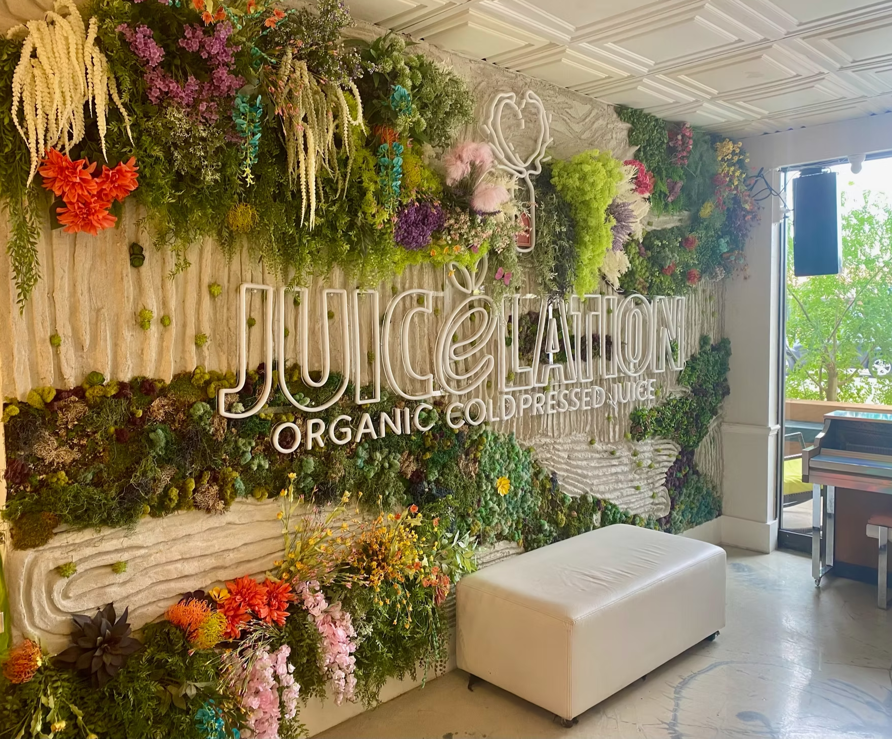 A JuiceLand storefront with a flower wall