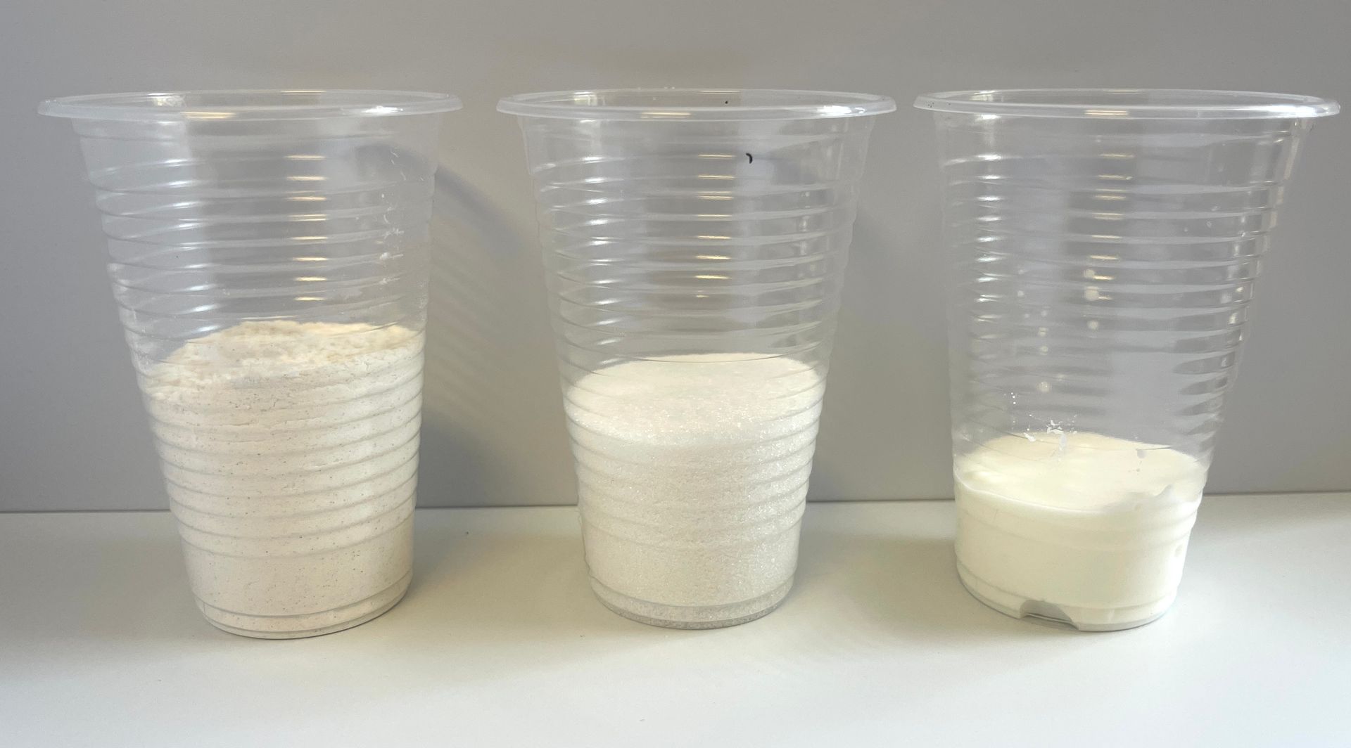 3 plastic cups with flour, sugar and corn starch in each.