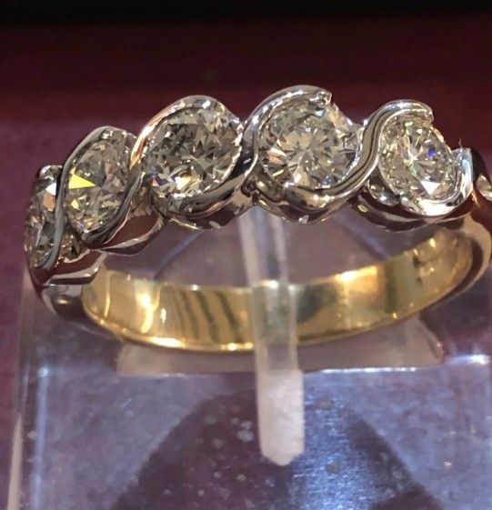 Diamond ring with five round diamonds in a swirling white gold and yellow gold band.