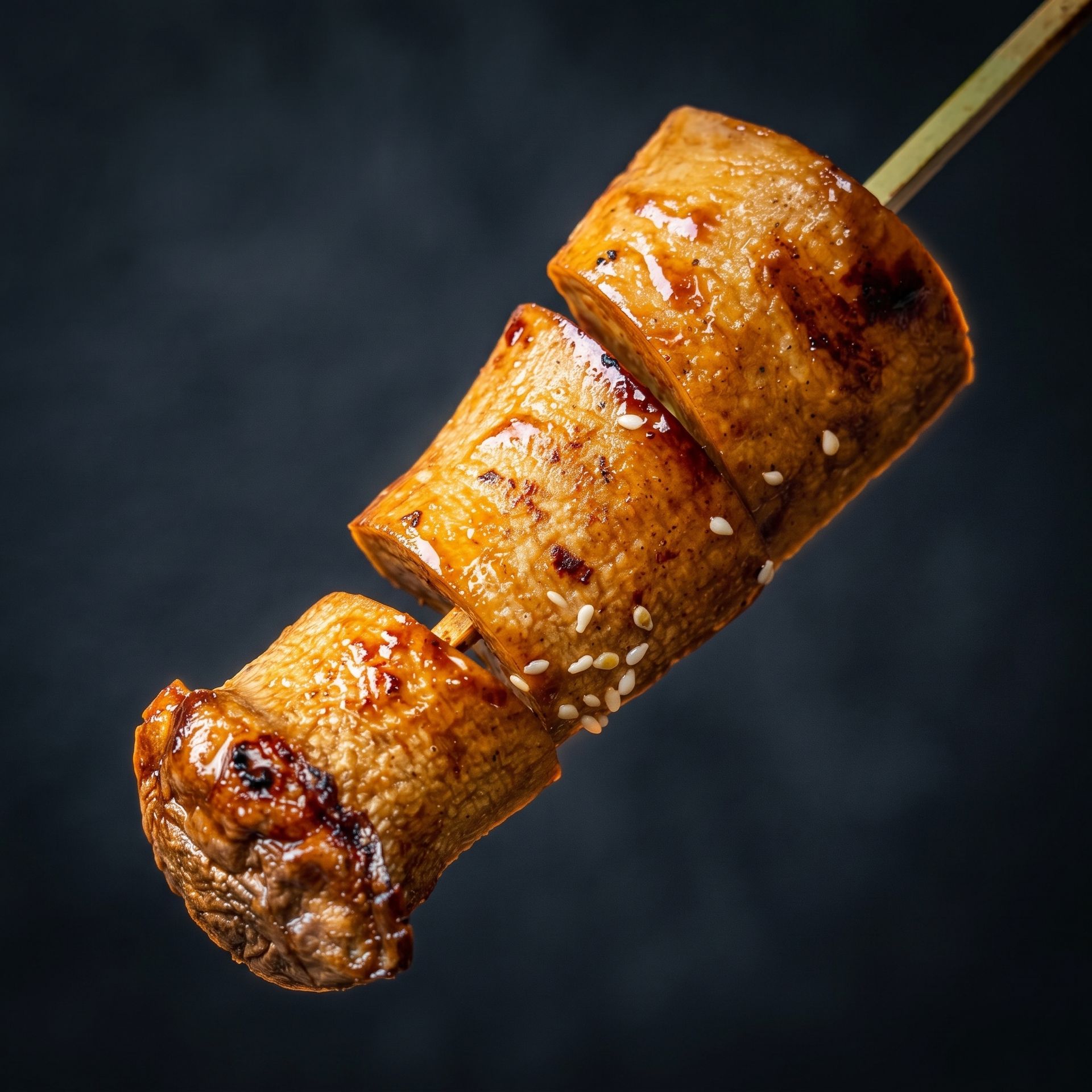 Grilled meat skewers with a golden-brown glaze on a dark background