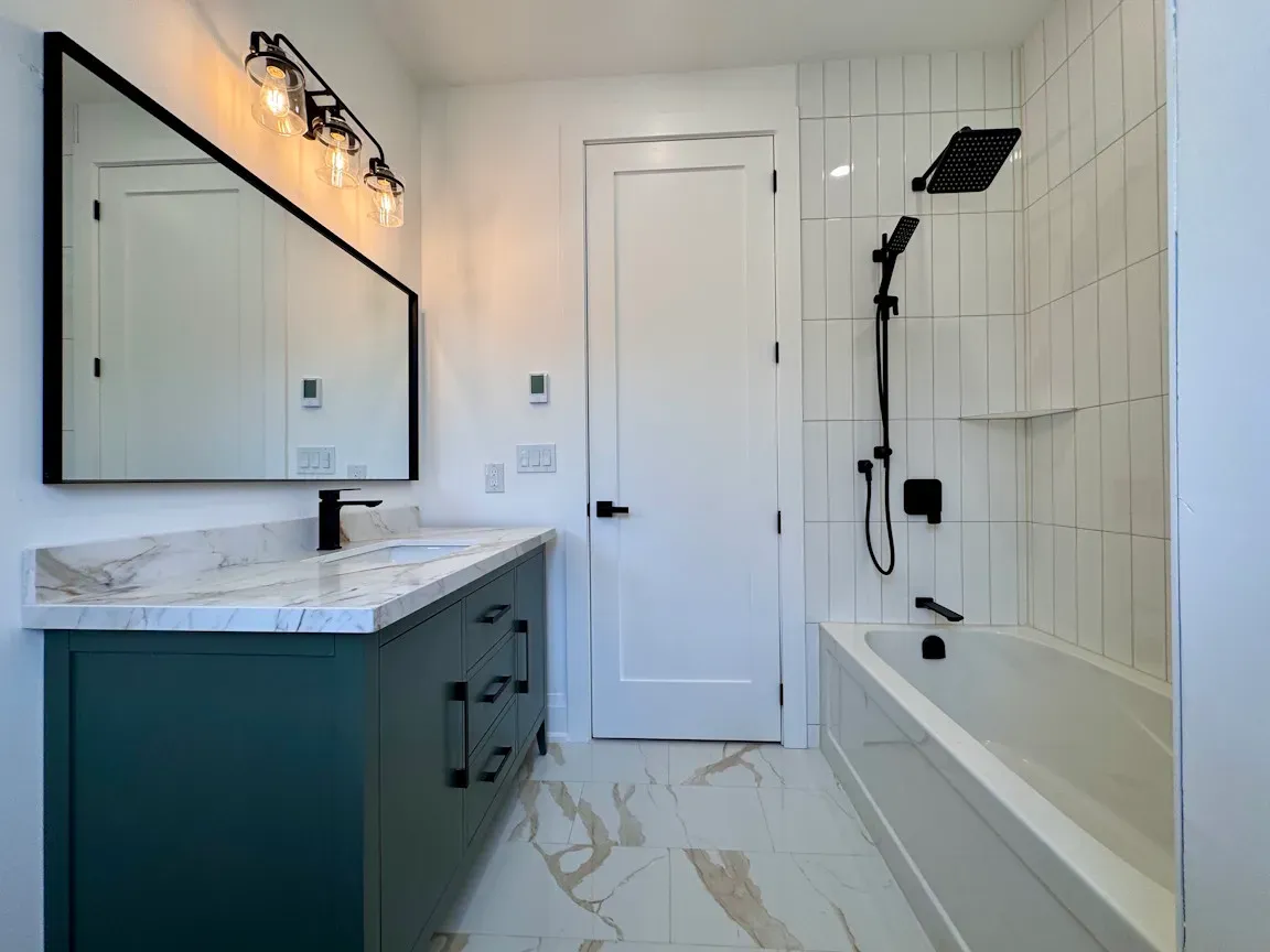 Main Bathroom - green vanity with subway tiles installed vertically with hand shower - farmhouse style