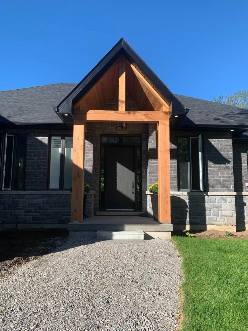 A single-story, stone-faced suburban house with a three-car garage, a covered front entrance, and a landscaped front lawn.