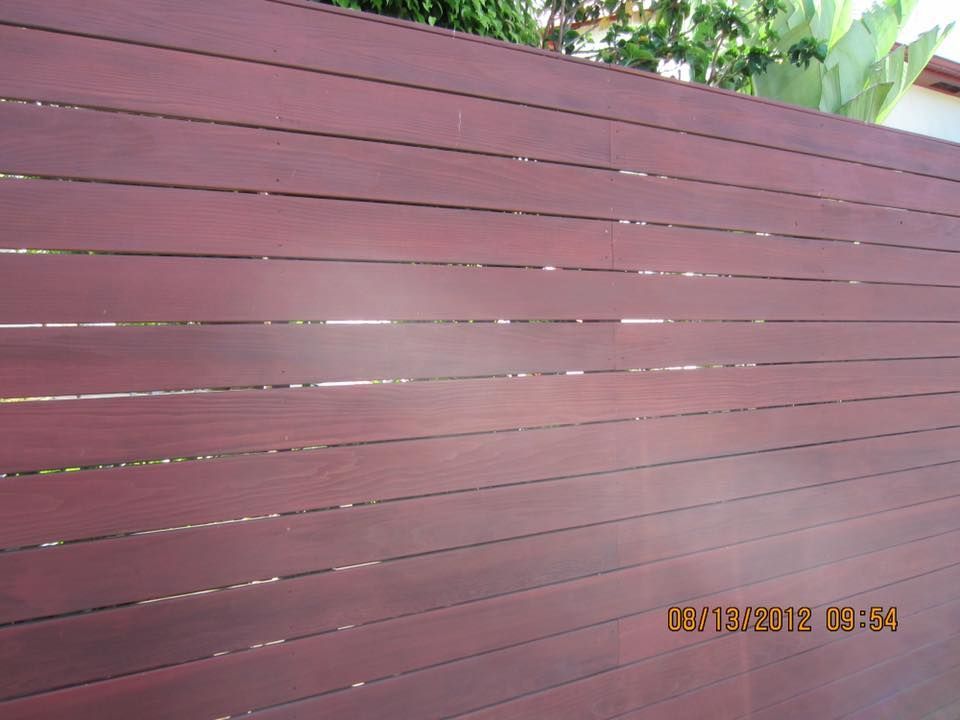 Red stained wood fence with horizontal slats.