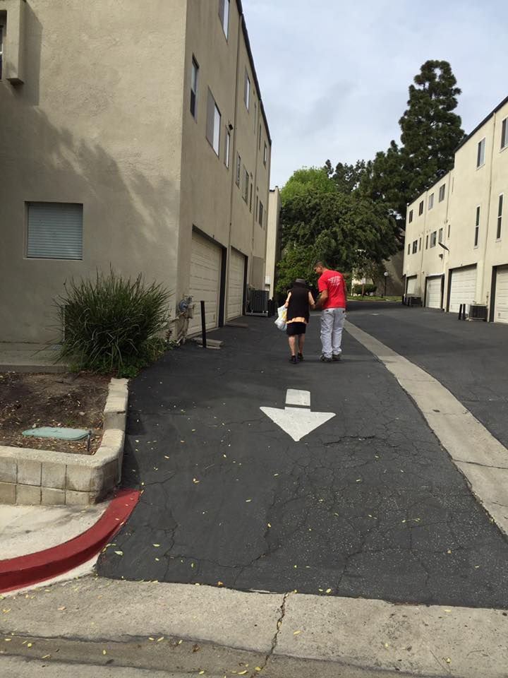 Two people walking down a paved alley between apartment buildings. Arrow painted on pavement.
